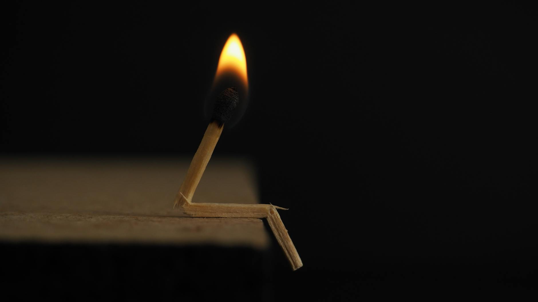 A creative capture of a bent matchstick with a burning flame against a dark backdrop. - treadmill fat burn