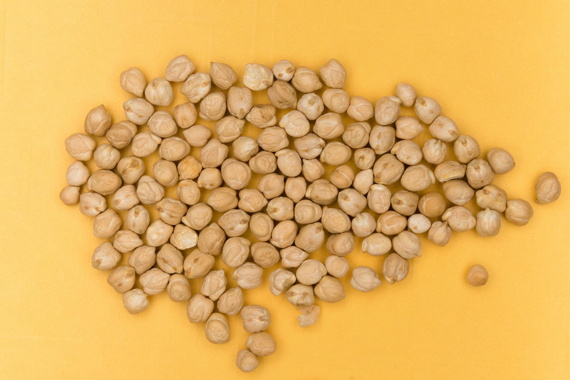 Close-up view of dried chickpeas on a vibrant yellow surface, emphasizing organic and healthy food. - vegetarian protein sources