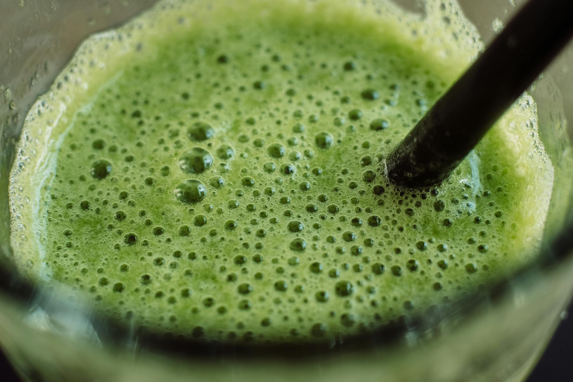 Close-up of a frothy green smoothie with bubbles and a straw for a fresh start. - water fast cleanse