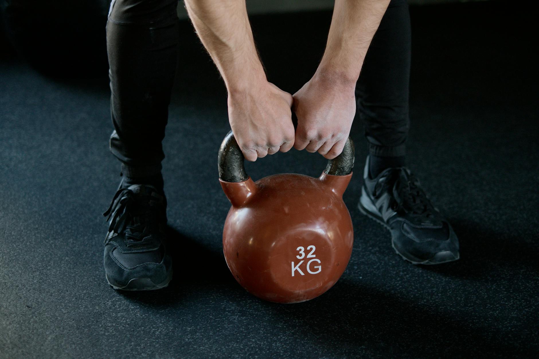 A person lifting a 32 kg kettlebell in a gym setting, showcasing strength training. - 30 minute workout