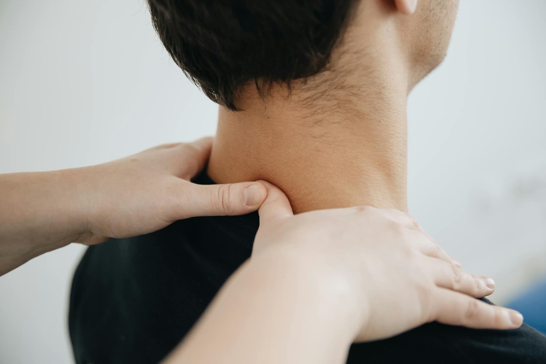 Close-up of a physiotherapist providing neck massage for pain relief in a clinic setting. - back pain relief
