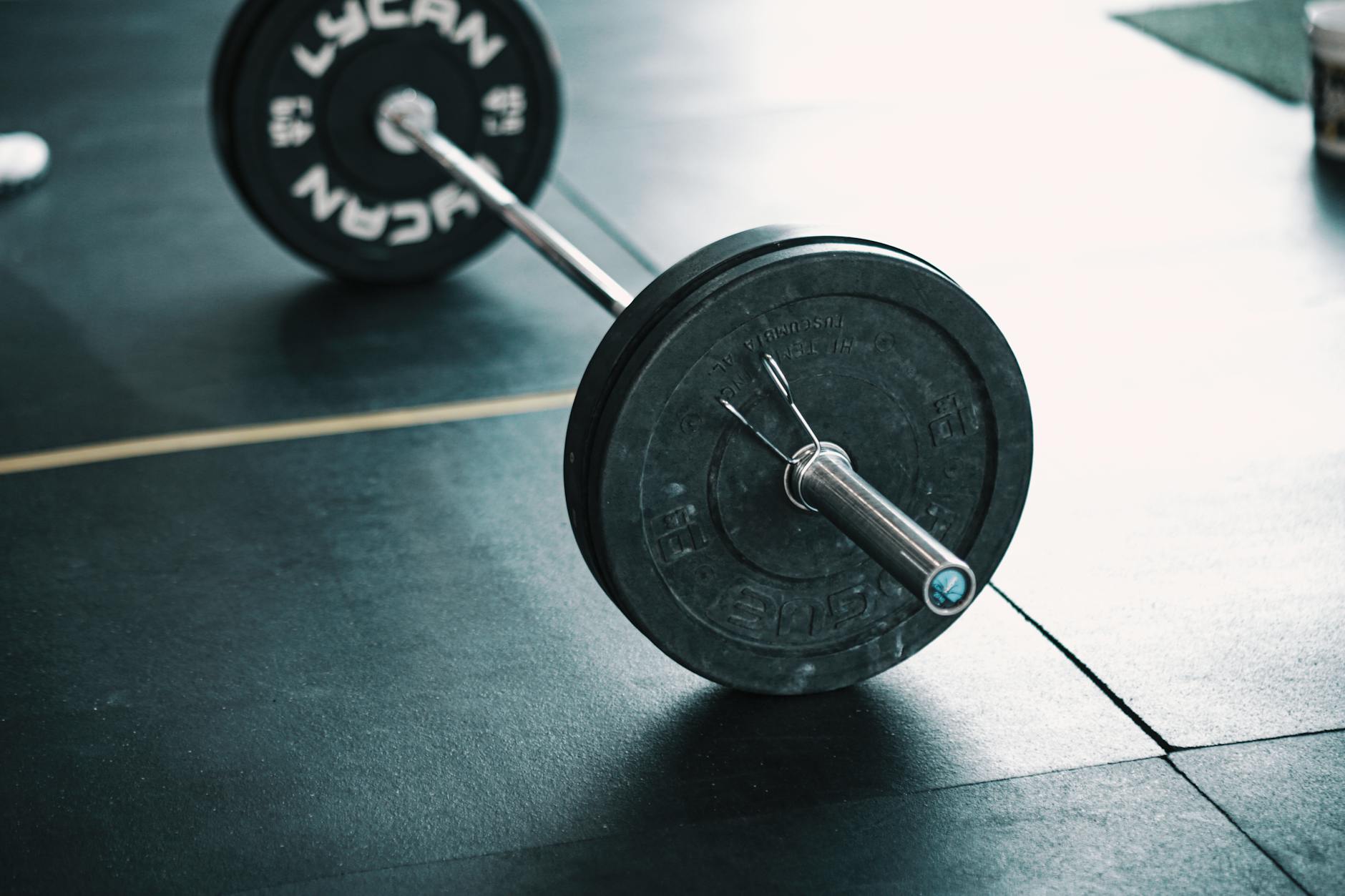 A detailed image of a barbell resting on a gym floor, perfect for fitness themes. - beginner strength training