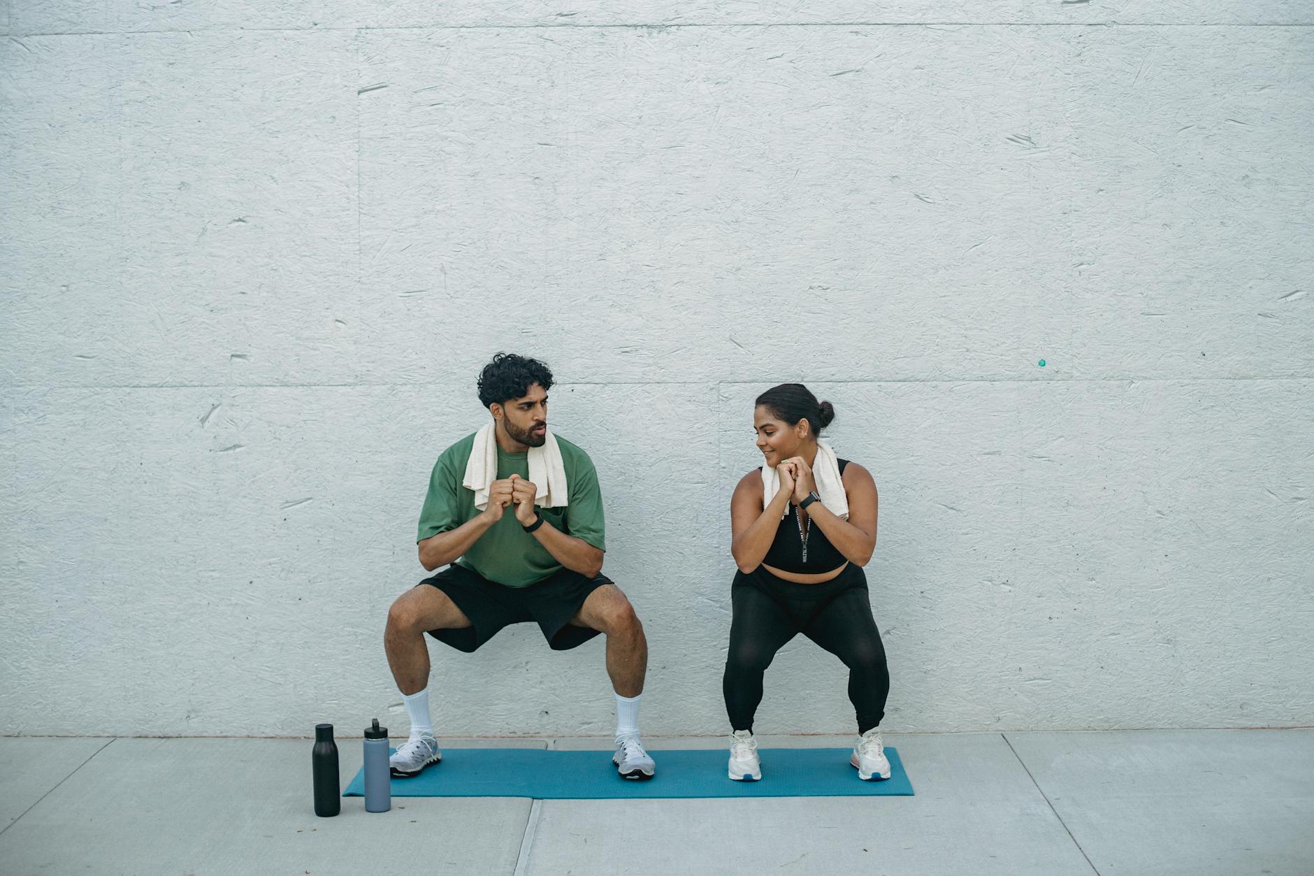 Man and woman exercising outdoors on a yoga mat, focusing on squats and healthy lifestyle. - beginner workouts