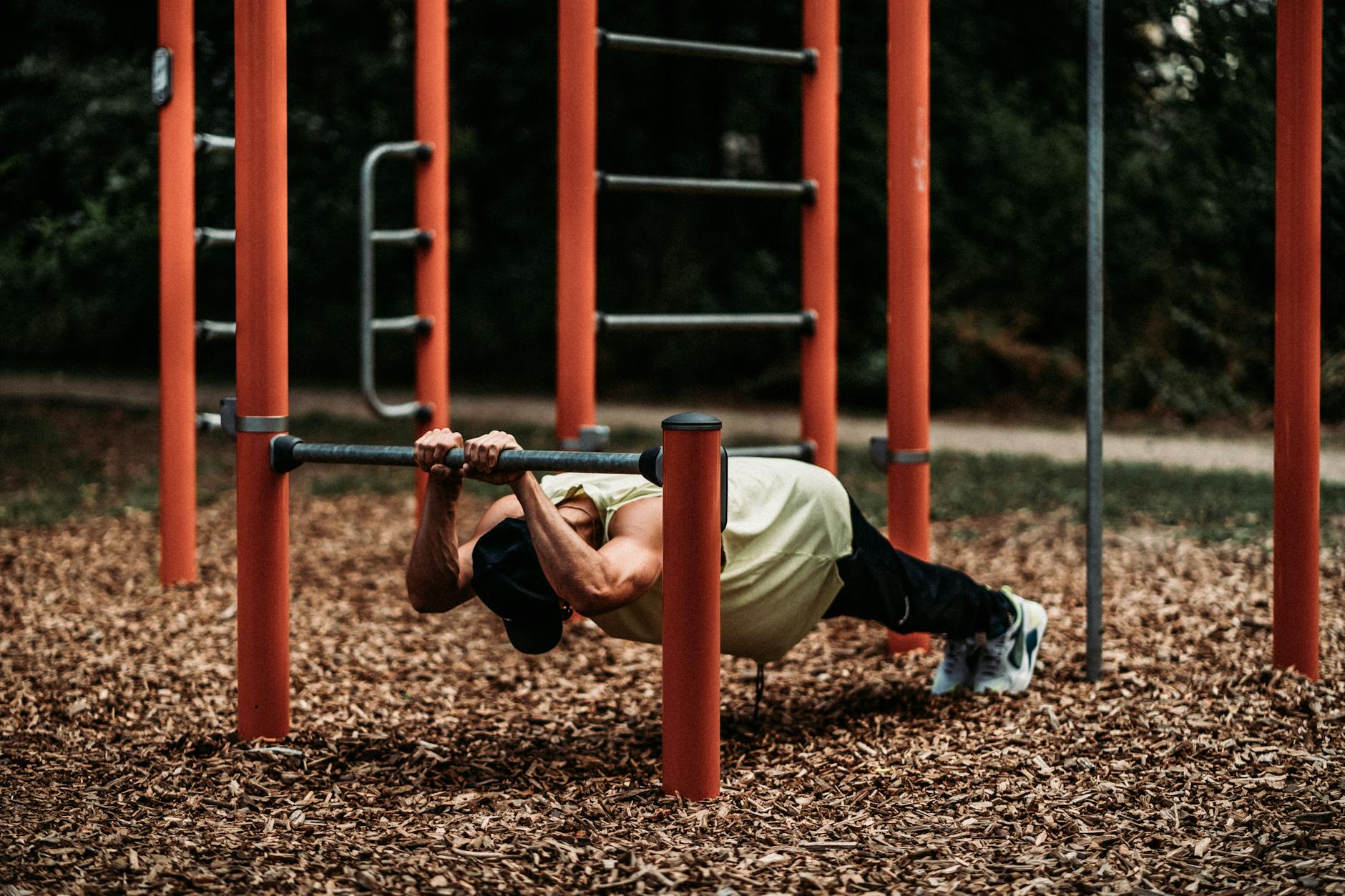 Strong man executes calisthenics on iron bars in a park, focusing on strength and balance. - bodyweight strength reset