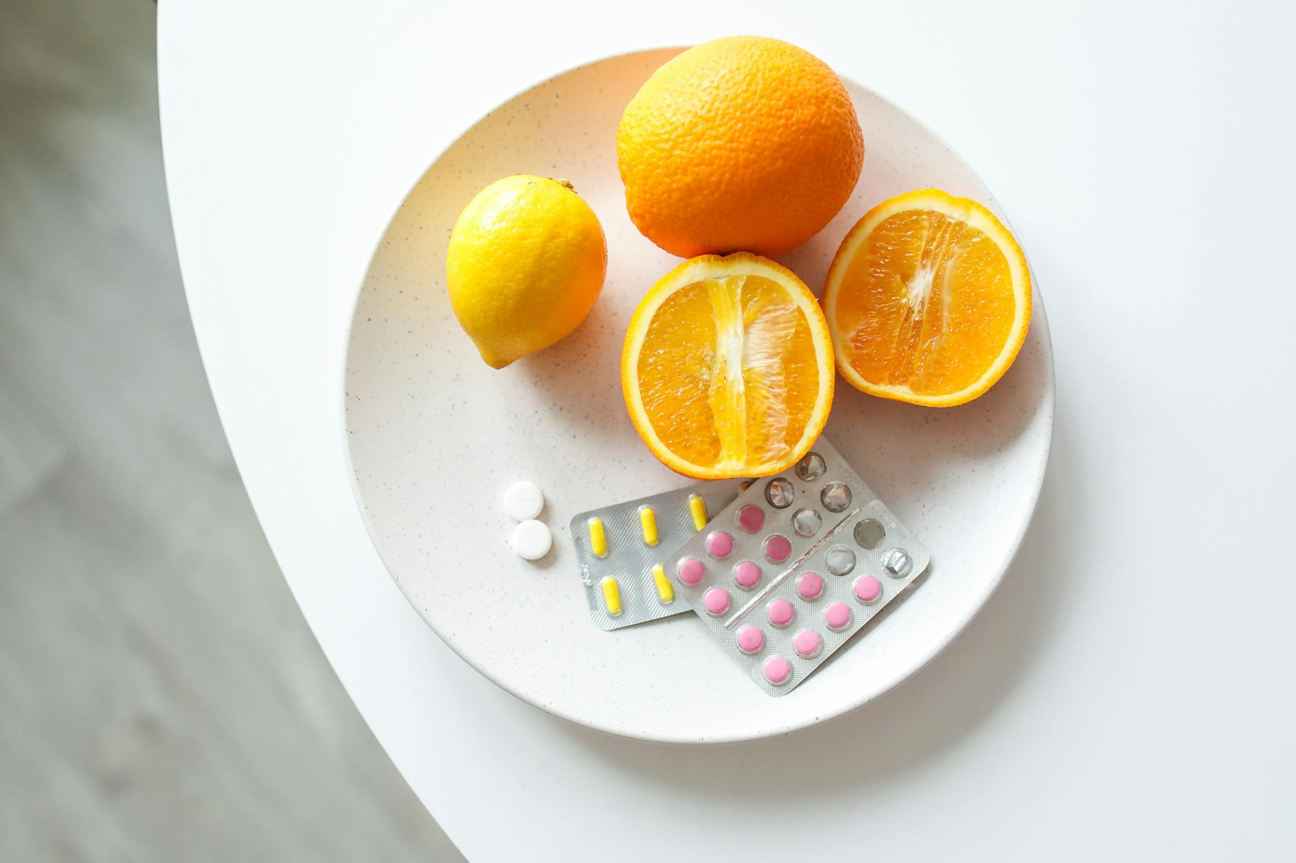 A plate of fresh citrus fruits and blister packs of pills, highlighting nutrition and healthcare. - boost immune system naturally