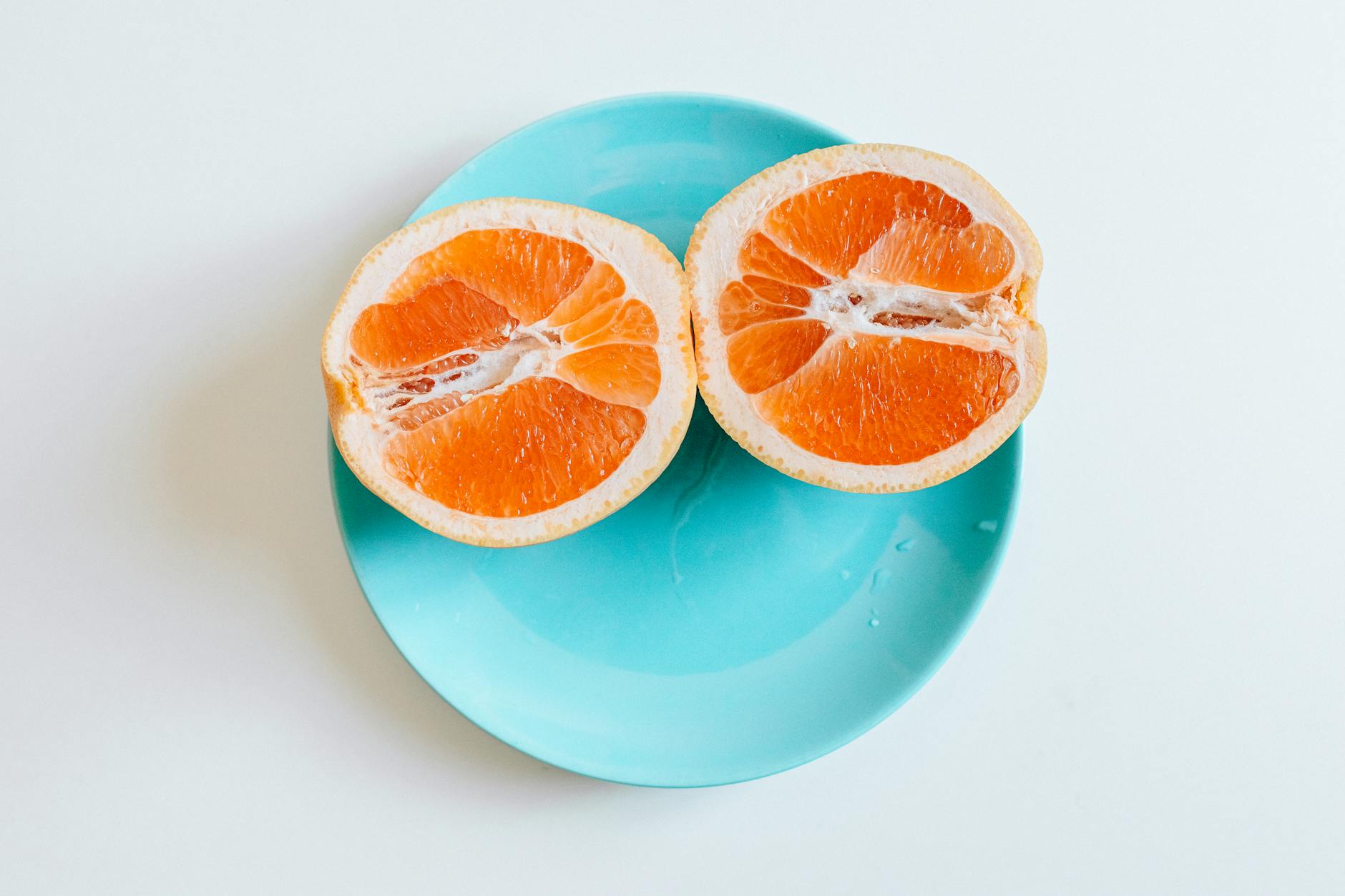 Vibrant halved grapefruit on a turquoise plate, showcasing fresh citrus appeal. - boost immune system naturally