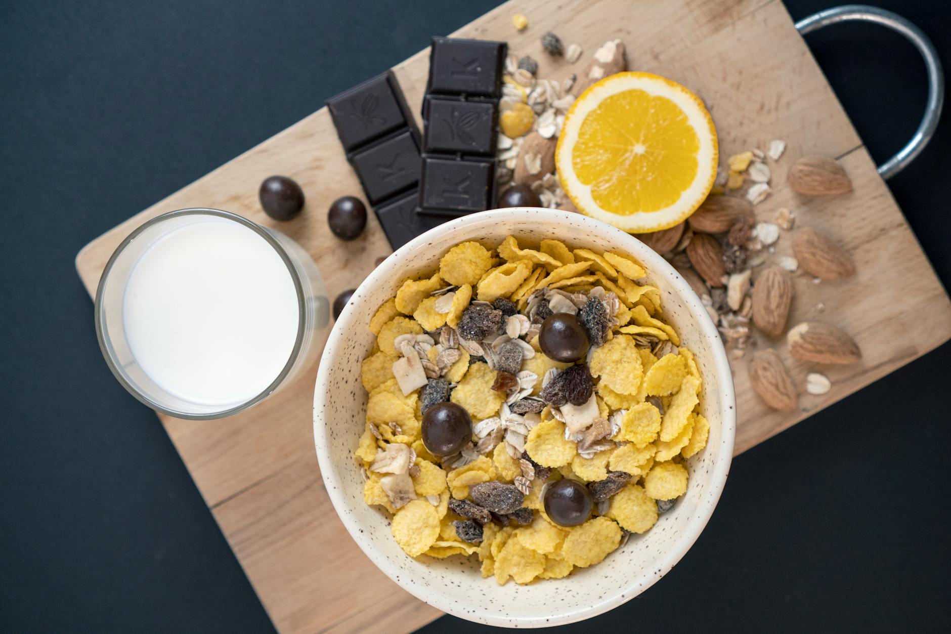 A close-up of a nutritious breakfast featuring cereal, chocolate, orange, and milk on a wooden board. - boost metabolism foods