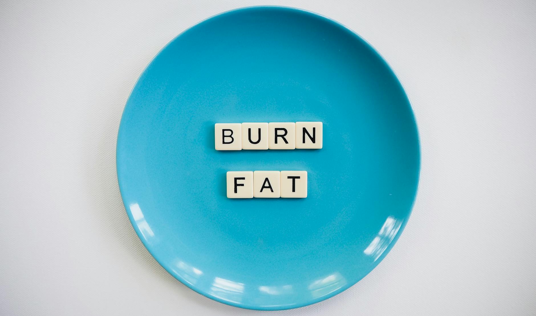 A conceptual image featuring the words 'Burn Fat' on a blue plate, symbolizing weight loss. - boost metabolism naturally