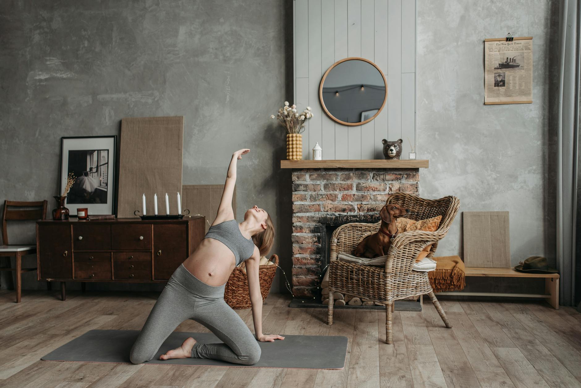 Pregnant woman practicing yoga near a fireplace with a dog in a cozy room. - chair yoga poses