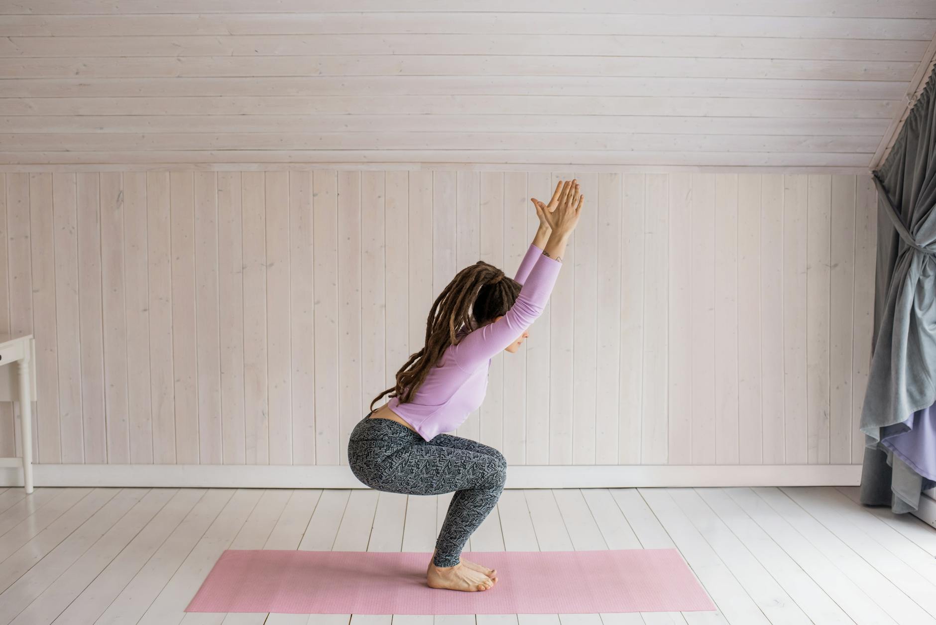 A woman performs yoga at home on a pink mat, emphasizing relaxation and health. - chair yoga poses