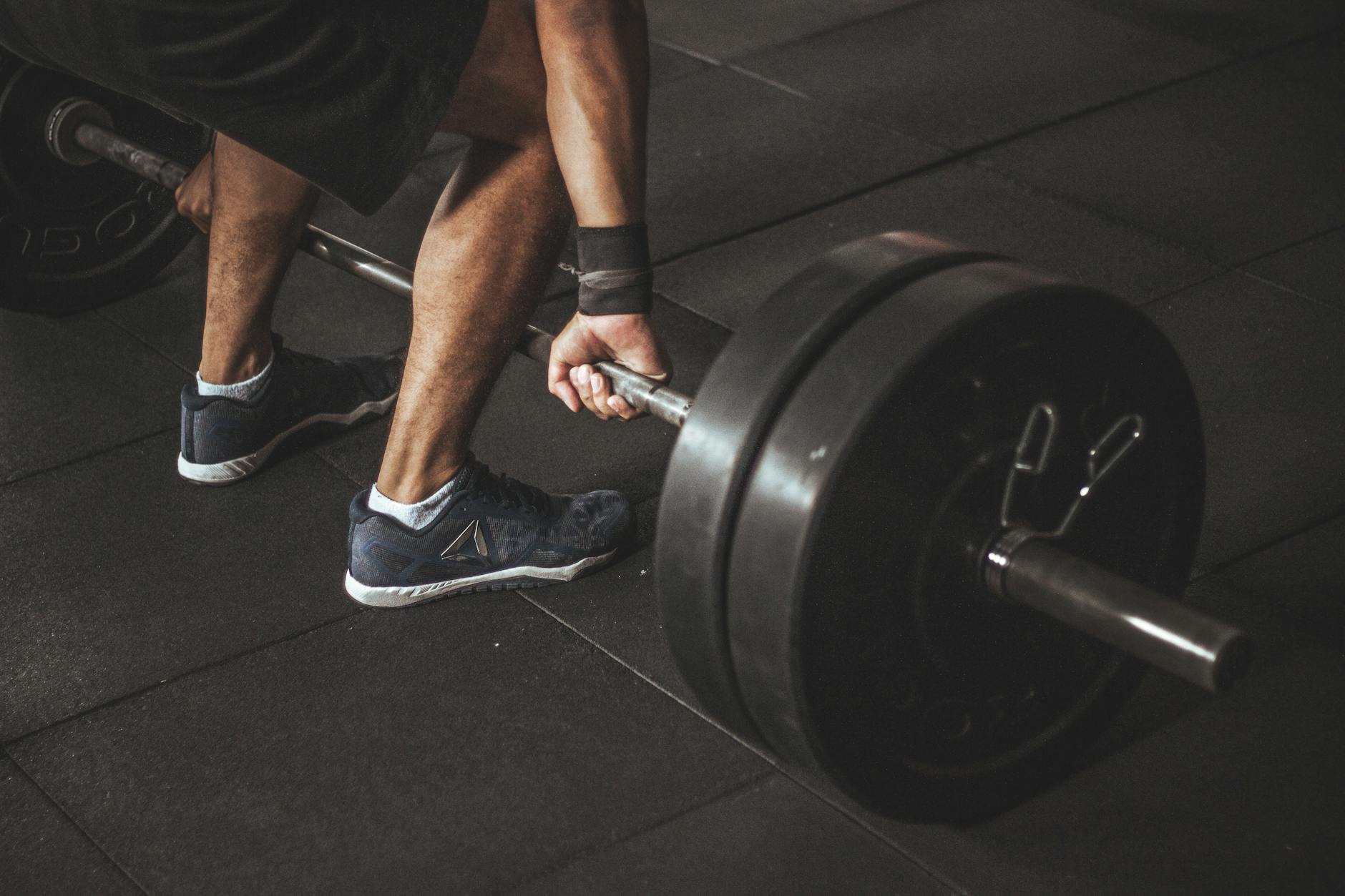A man lifting a heavy barbell during a gym workout, showcasing strength and fitness. - creatine benefits