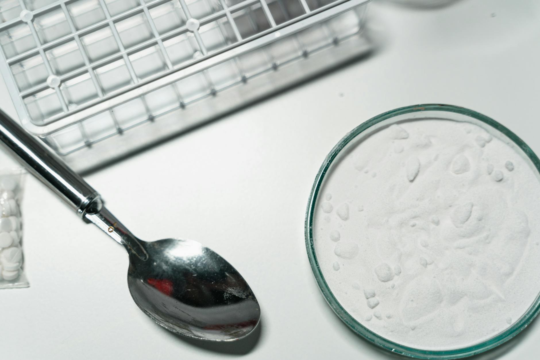 Metal spoon and white powder on a white countertop, suggesting substance use. - creatine benefits