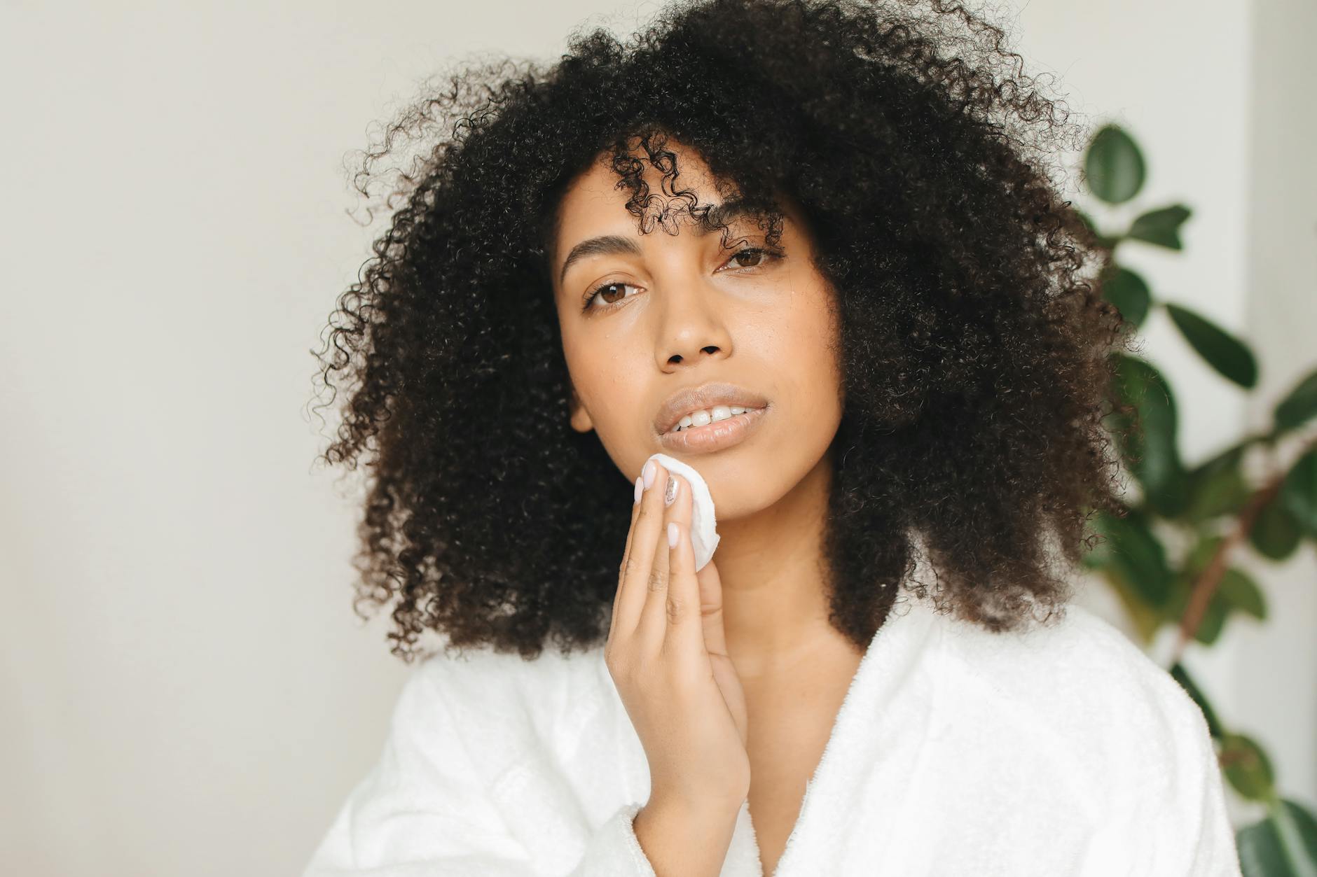 Capture of a woman gently cleansing her face with a cotton pad indoors. - daily skincare routine