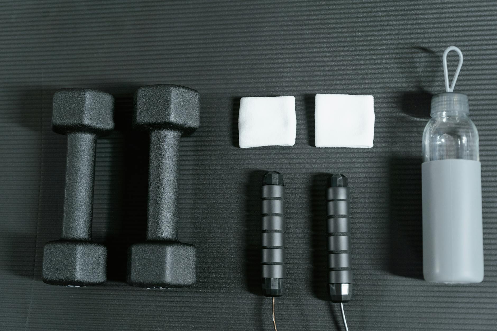 Flat lay of dumbbells, jump rope, and other gym essentials for a healthy lifestyle. - no equipment workouts