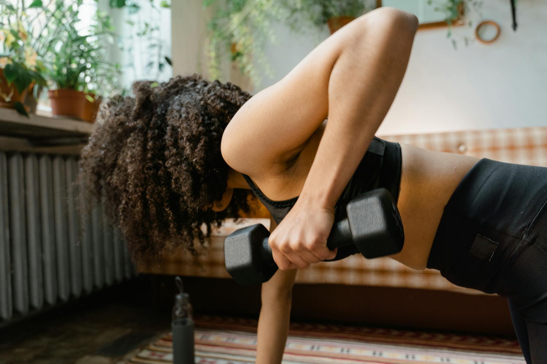 African American woman working out with dumbbells in an indoor setting, promoting a healthy lifestyle. - no equipment workouts
