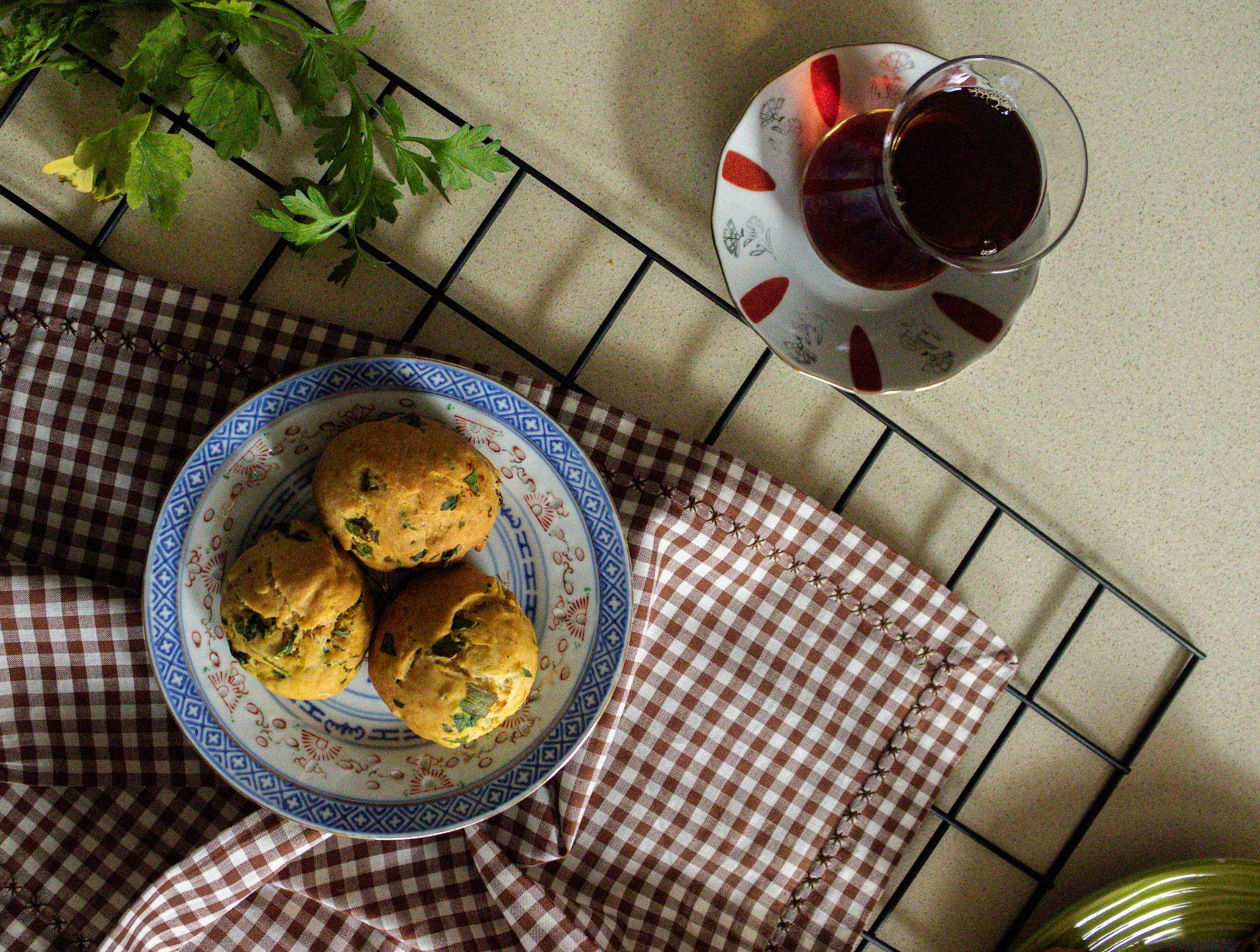 Top view of freshly baked herb muffins served with tea on a checkered cloth setting. - healthy breakfast muffins
