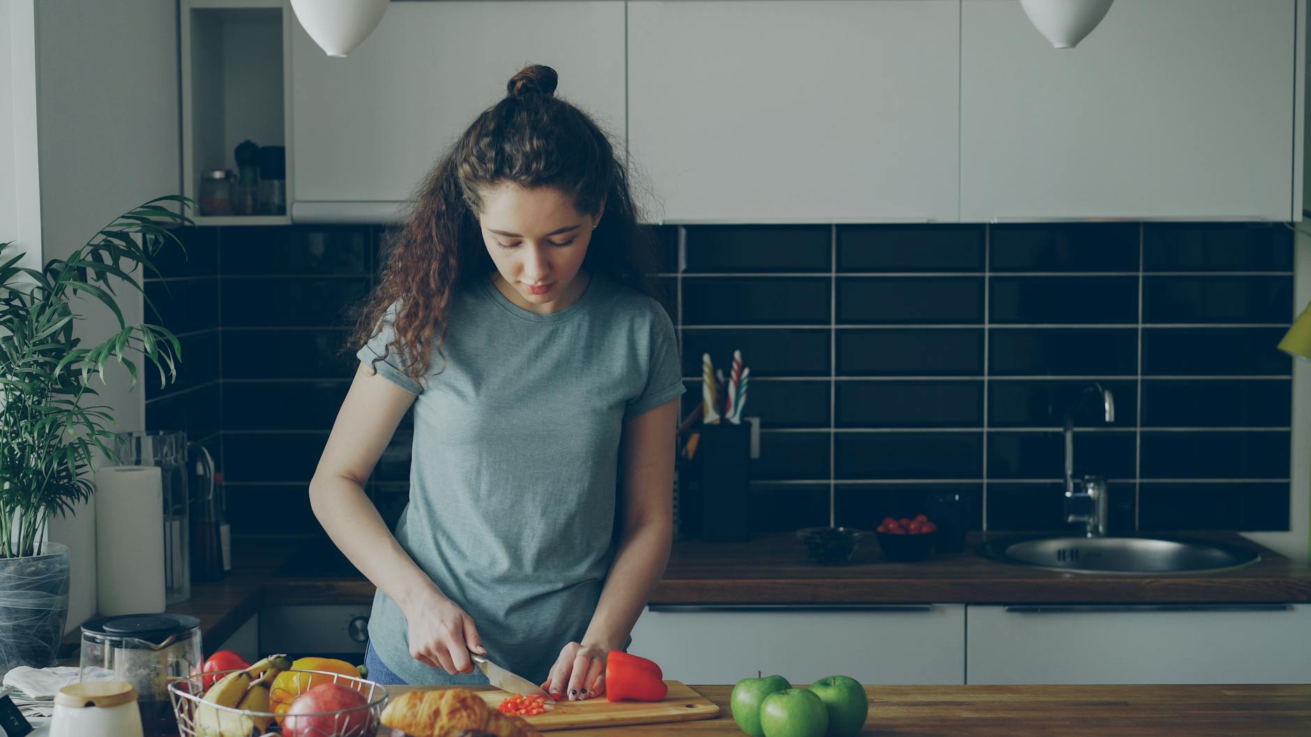 Young woman preparing food in a modern kitchen setting, cutting vegetables. - healthy casserole recipes