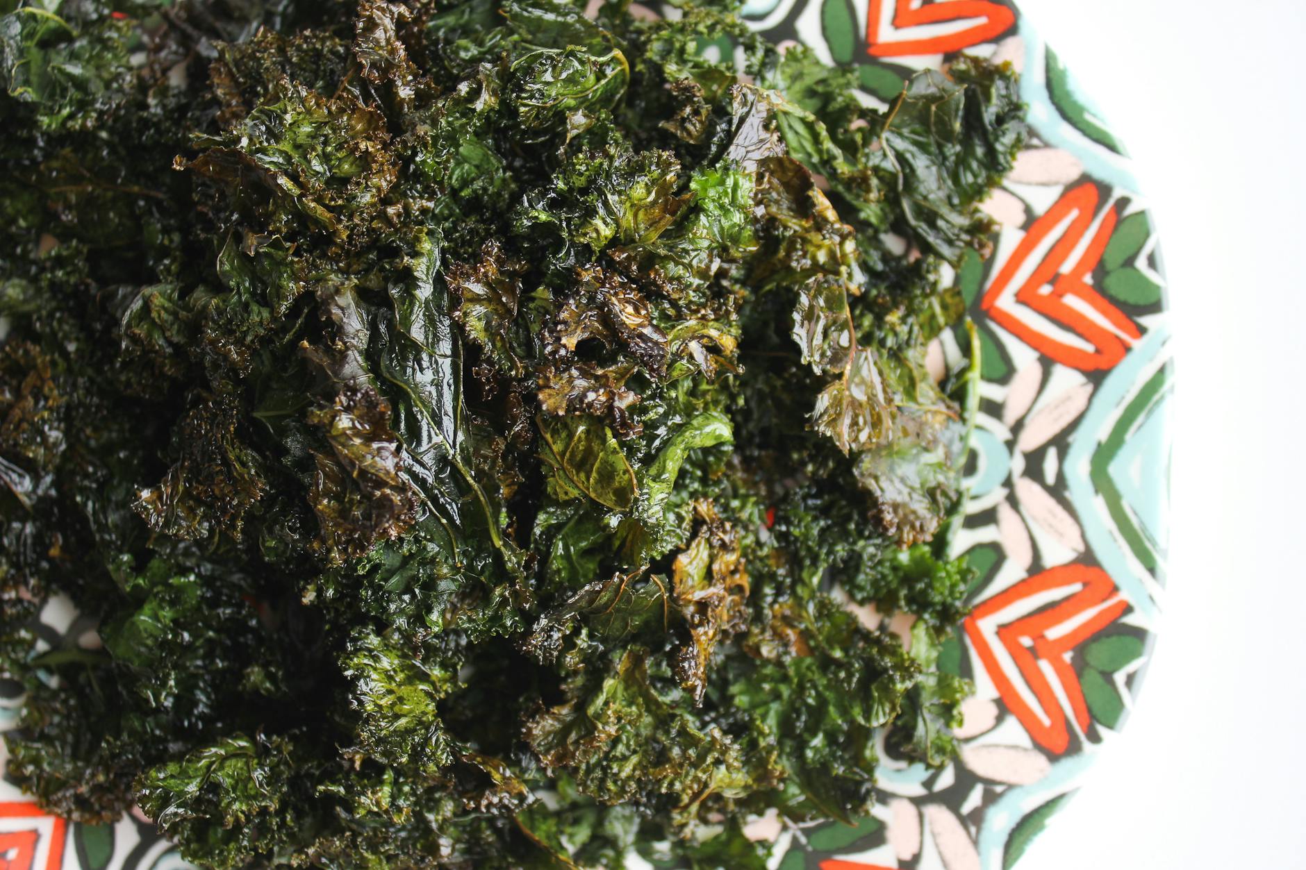 Delicious homemade baked kale chips served on a colorful patterned plate. - healthy snack recipes
