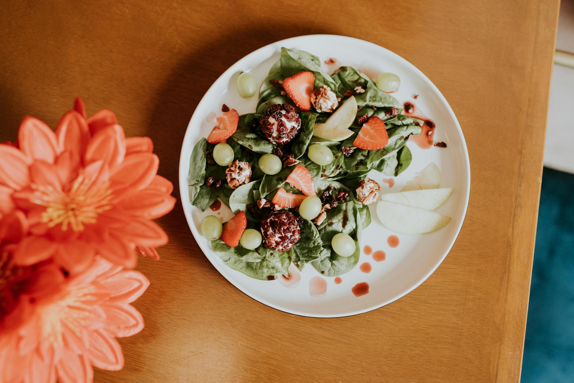 A vibrant salad of spinach, strawberries, grapes, and vinaigrette on a wooden table. - healthy spring salads