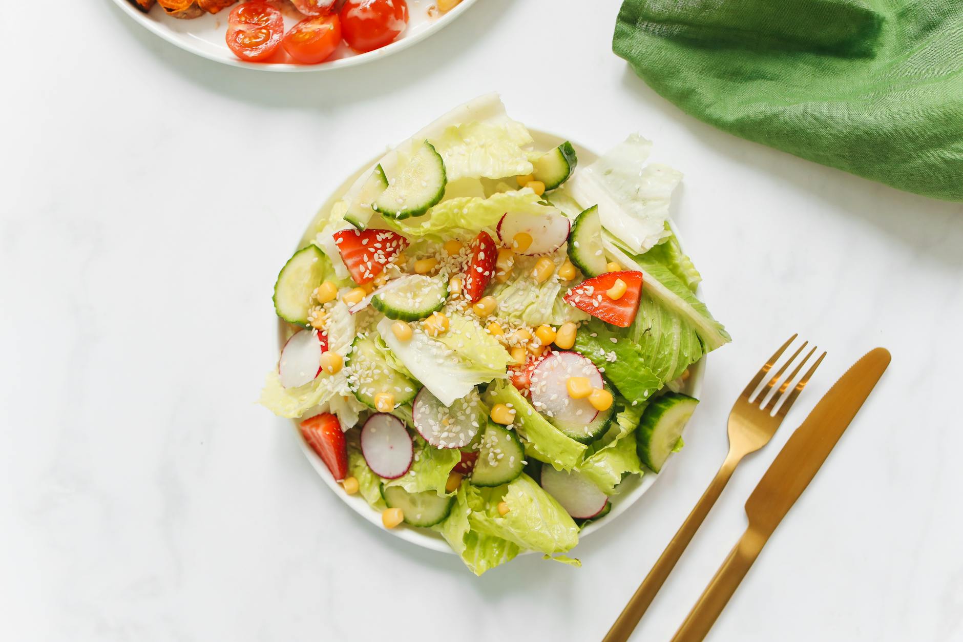 Colorful vegetable salad with lettuce, cucumbers, and radishes on a white plate. - healthy spring salads
