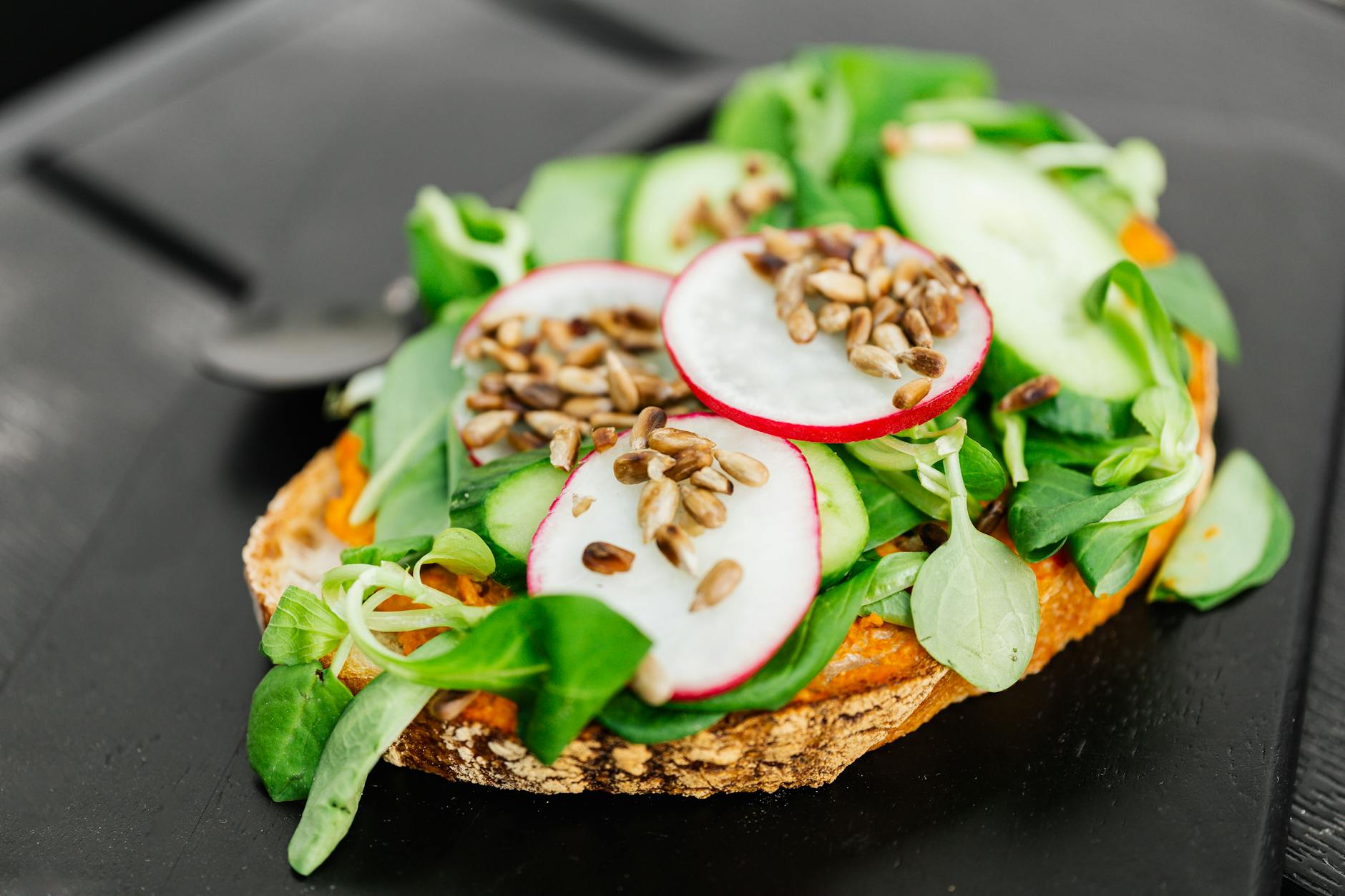 Delicious and nutritious open-faced vegetable toast with fresh greens, radishes, and seeds, perfect for a healthy snack. - healthy spring snacks