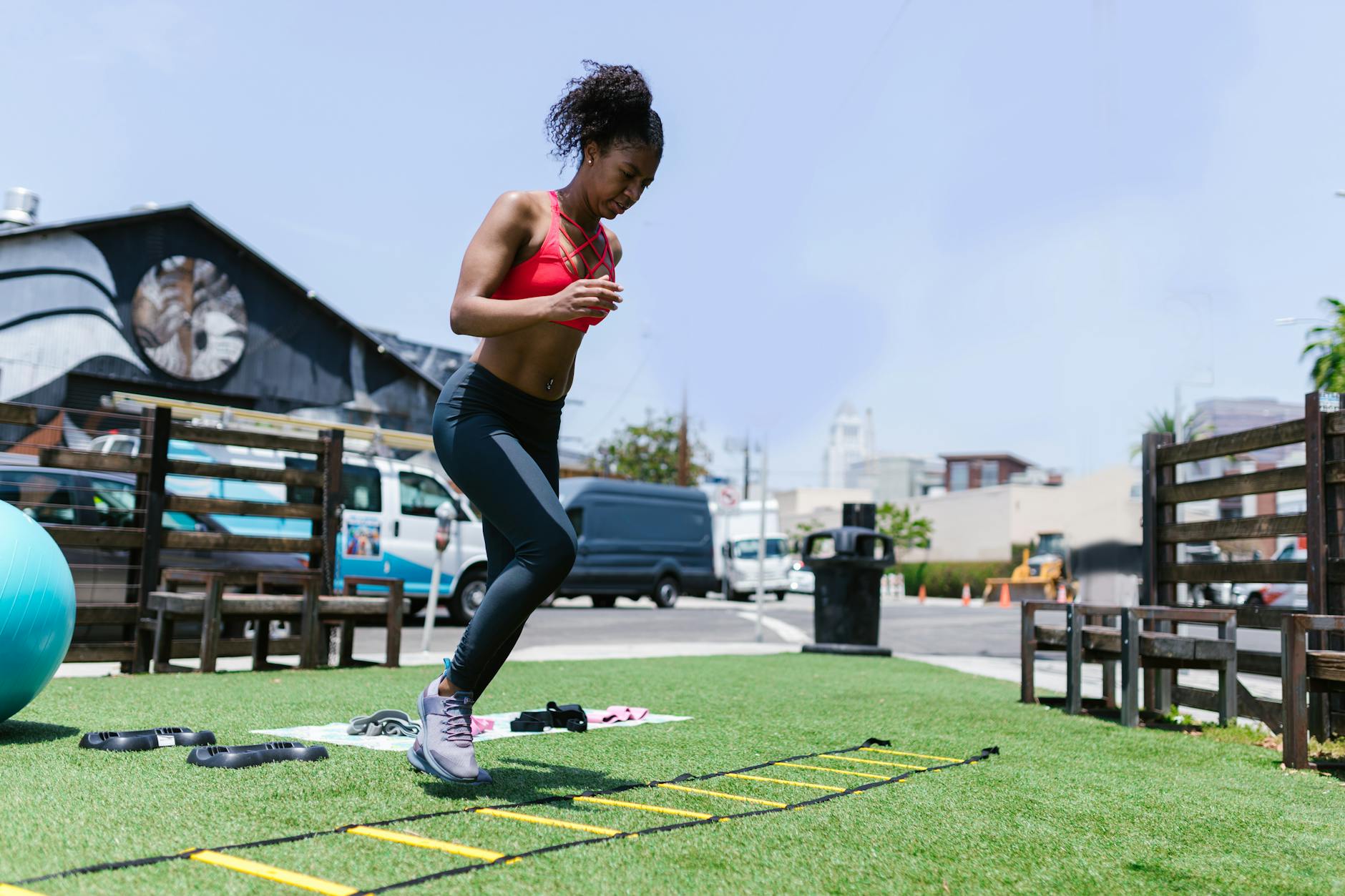 Black woman performing fitness exercises using agility ladder outdoors - hiit for busy people