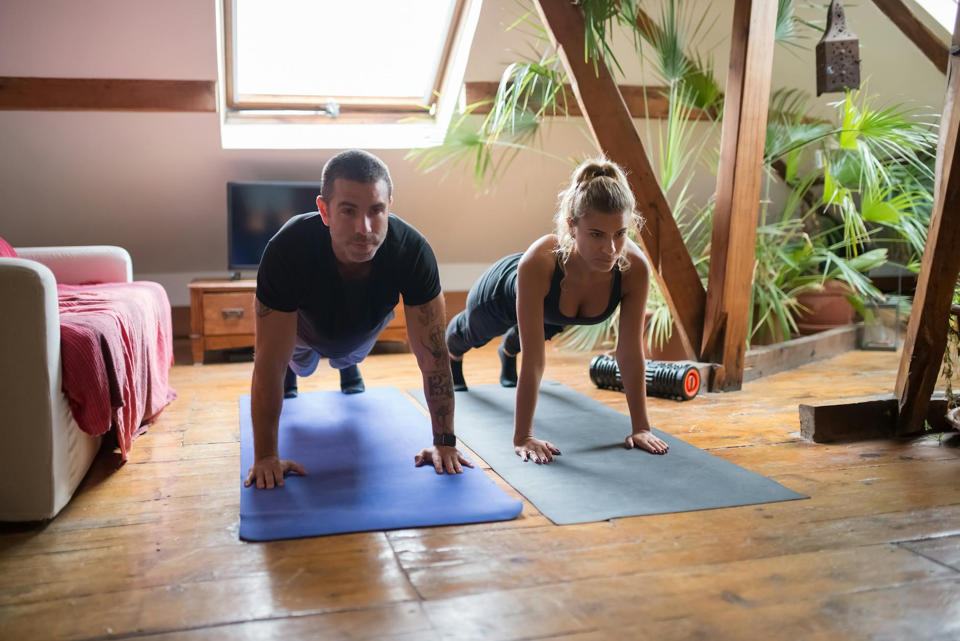 A man and woman doing push-ups together on yoga mats in a cozy home setting. - hiit workout at home