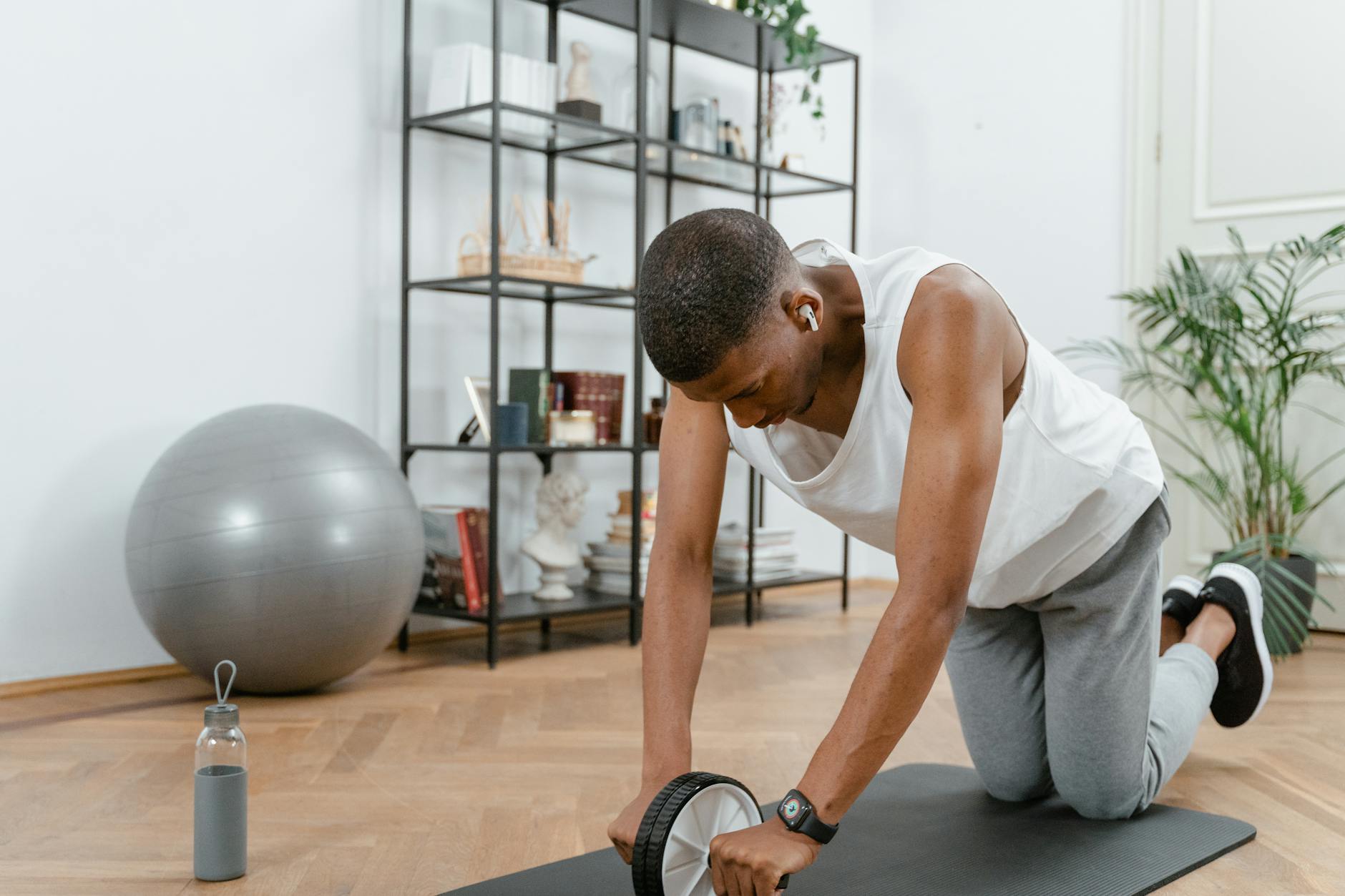 Adult male using an ab wheel for exercise in a home gym setting, focusing on fitness. - hiit workout at home