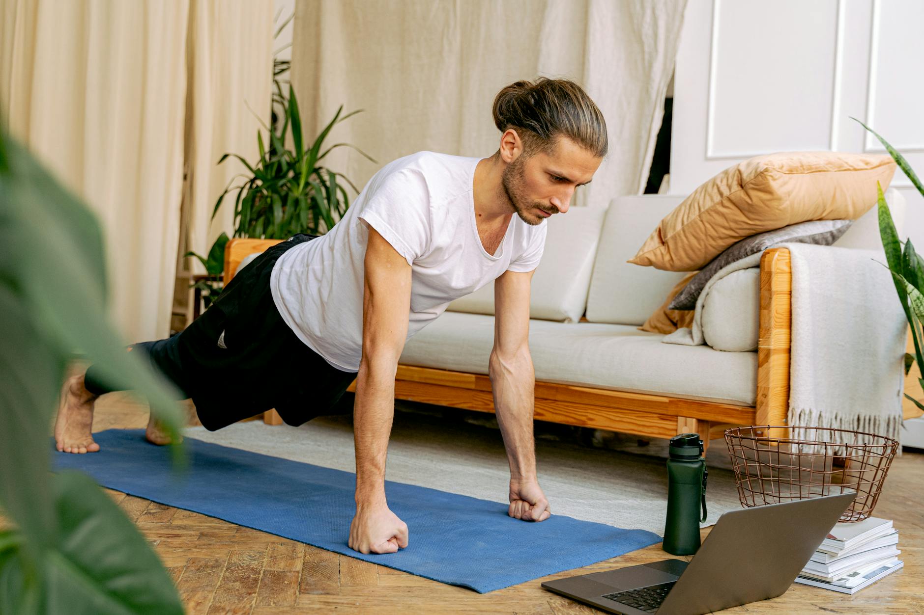 Man doing push-ups indoors on a yoga mat, engaging in a healthy lifestyle using online fitness resources. - hiit workout at home