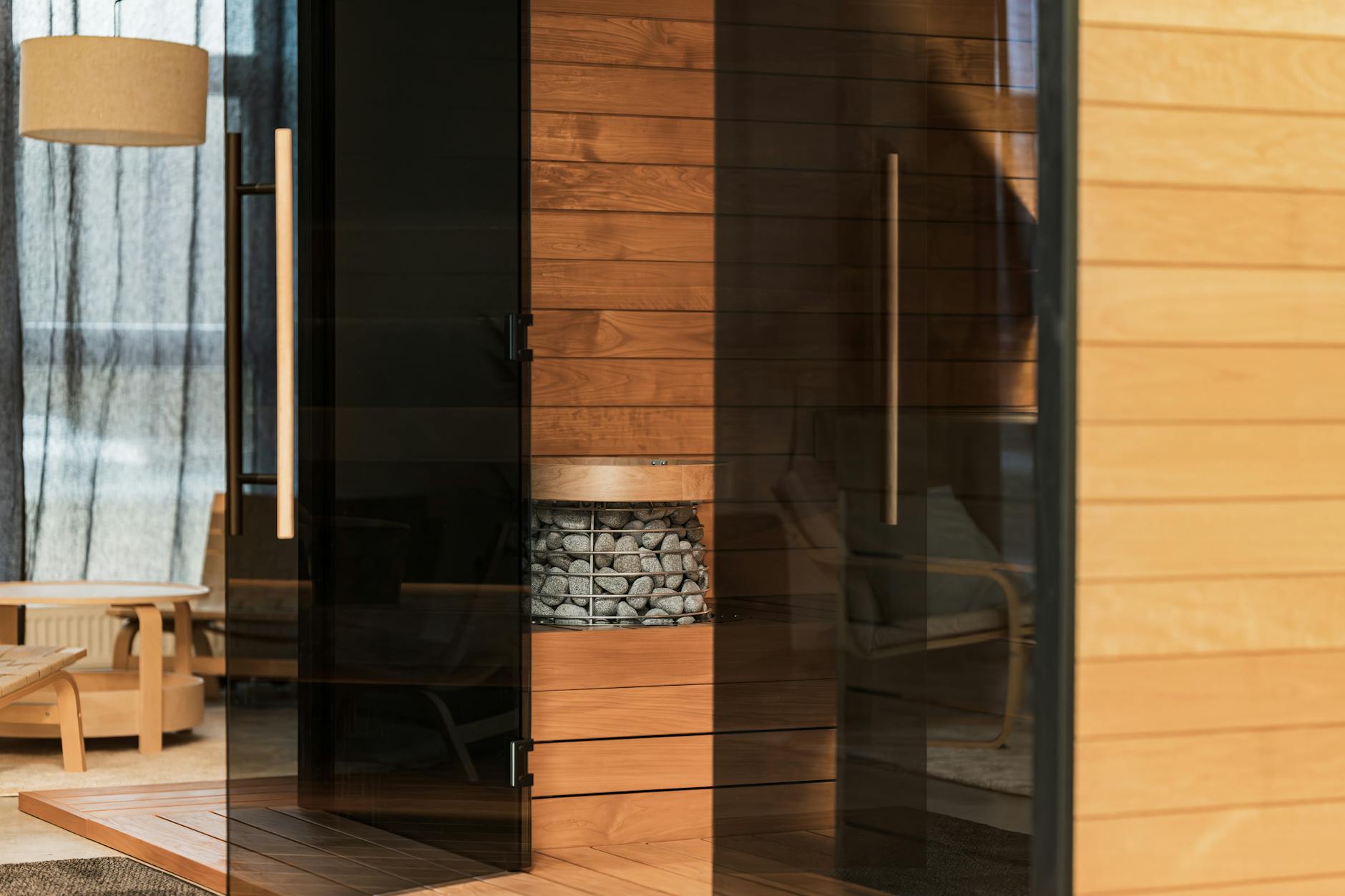 Elegant and modern indoor sauna featuring a Scandinavian design with wood panels and glass doors. - home wellness retreat