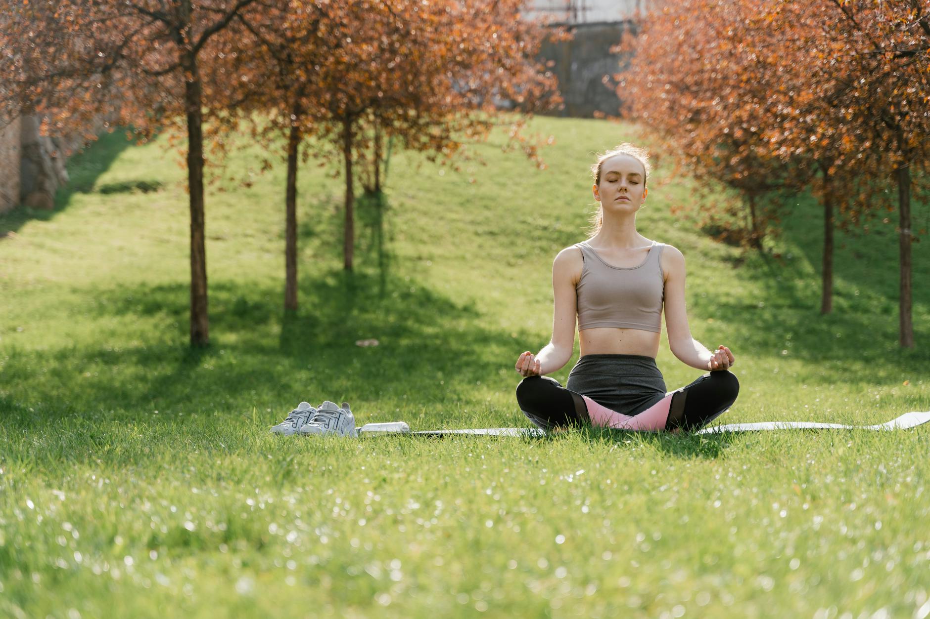 Woman practicing meditation in a sunny park, enhancing wellness and mindfulness. - mental clarity spring