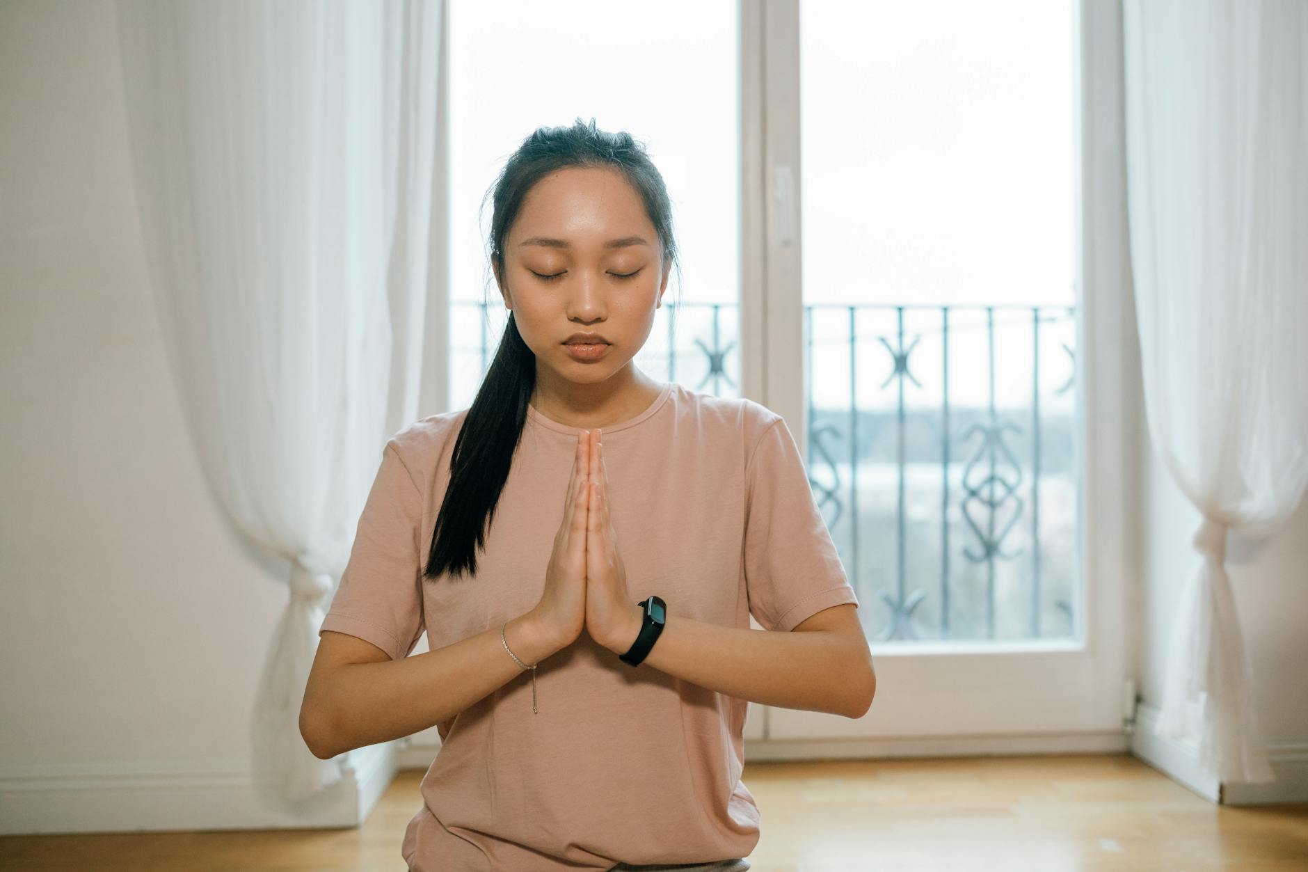 Asian woman practicing meditation indoors, hands together, promoting peace and healthy lifestyle. - mental clarity tips