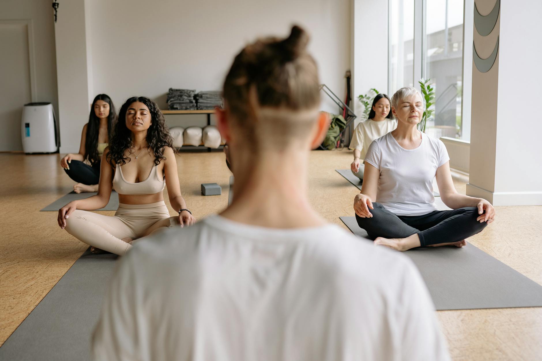 Peaceful meditation session with diverse group practicing yoga indoors. - what is mindfulness