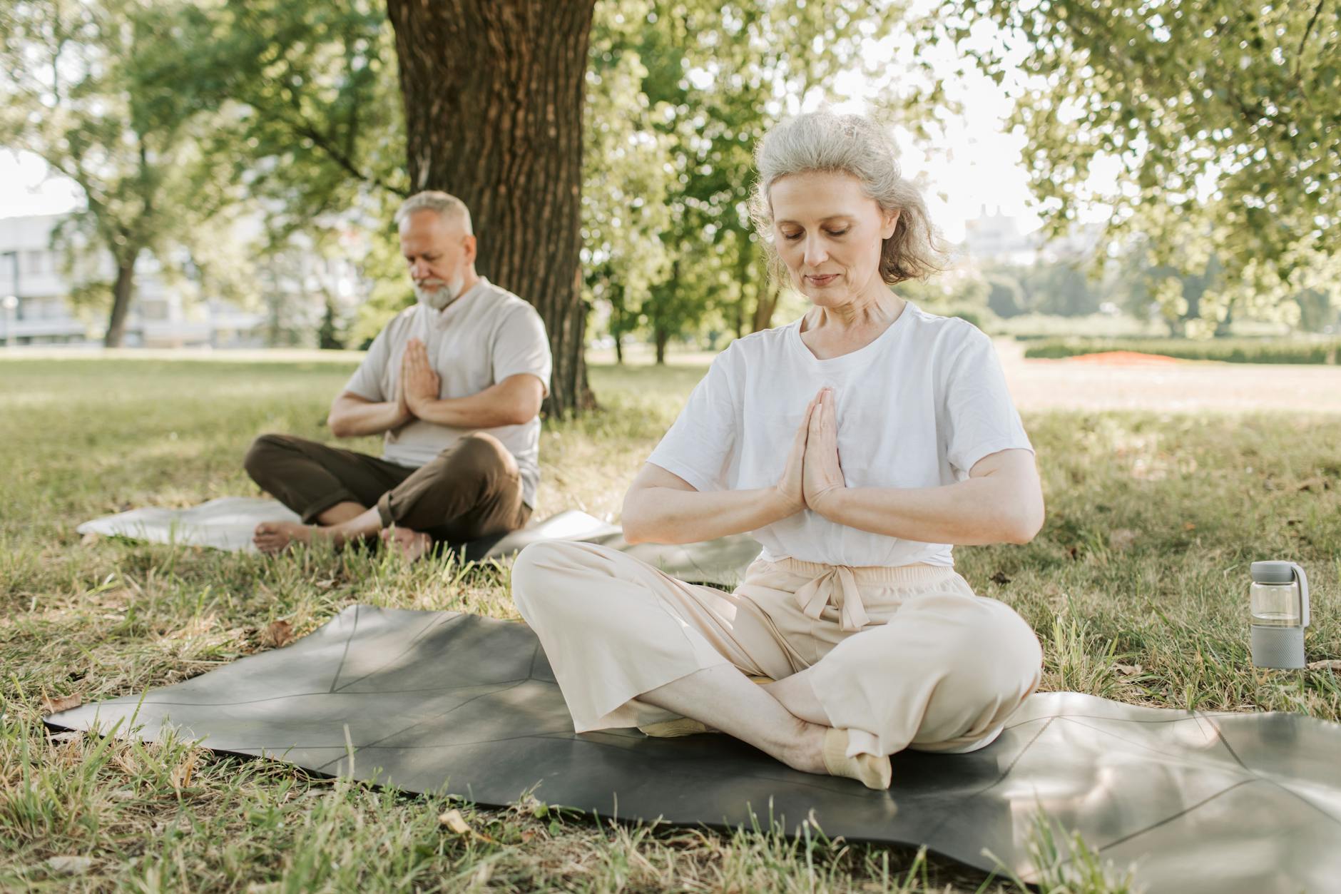 Elderly couple practicing yoga meditation outdoors, focusing on health and tranquility. - what is mindfulness