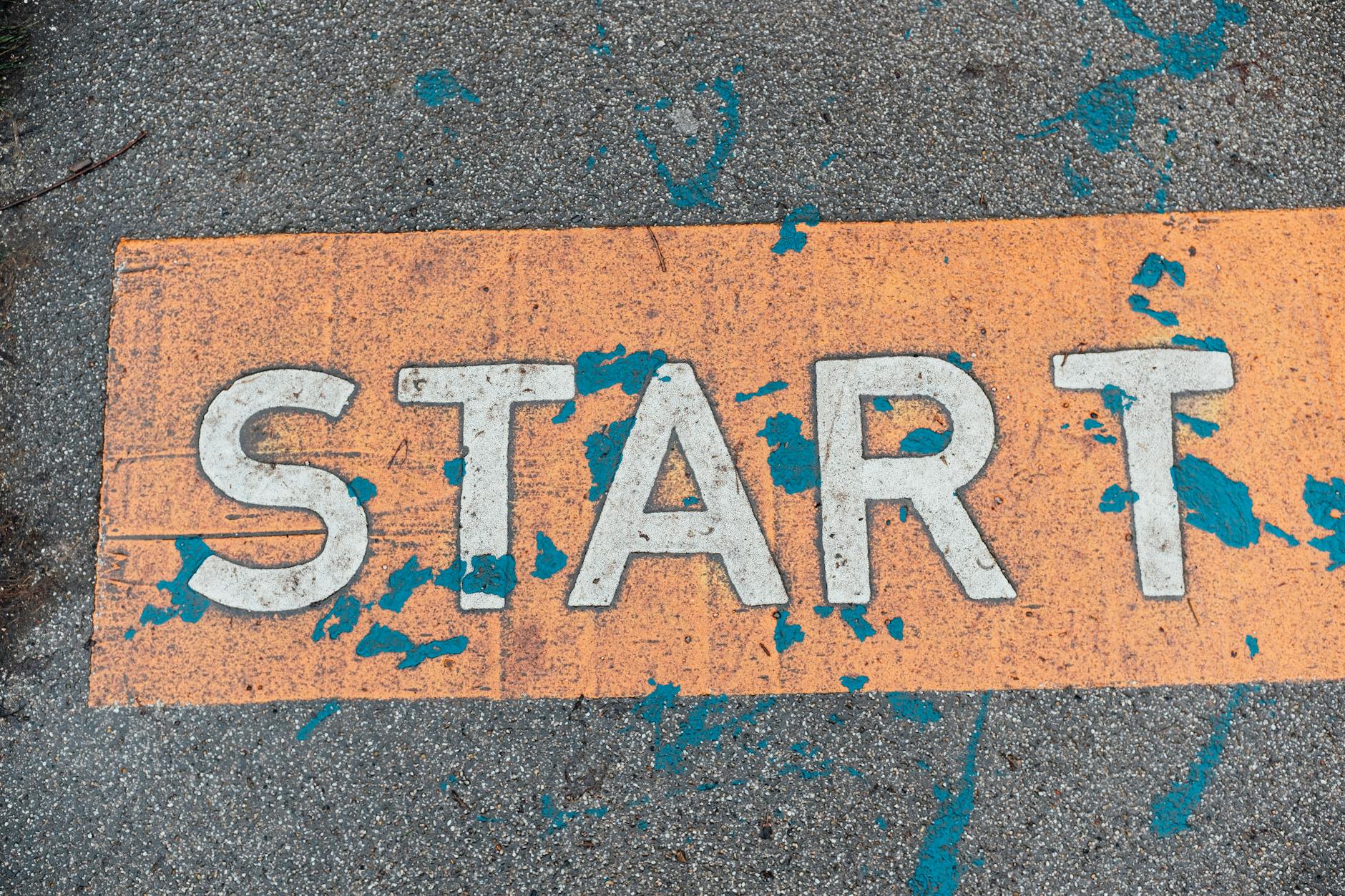 A worn orange start line painted on urban pavement with blue splatters. - mindfulness for fresh start