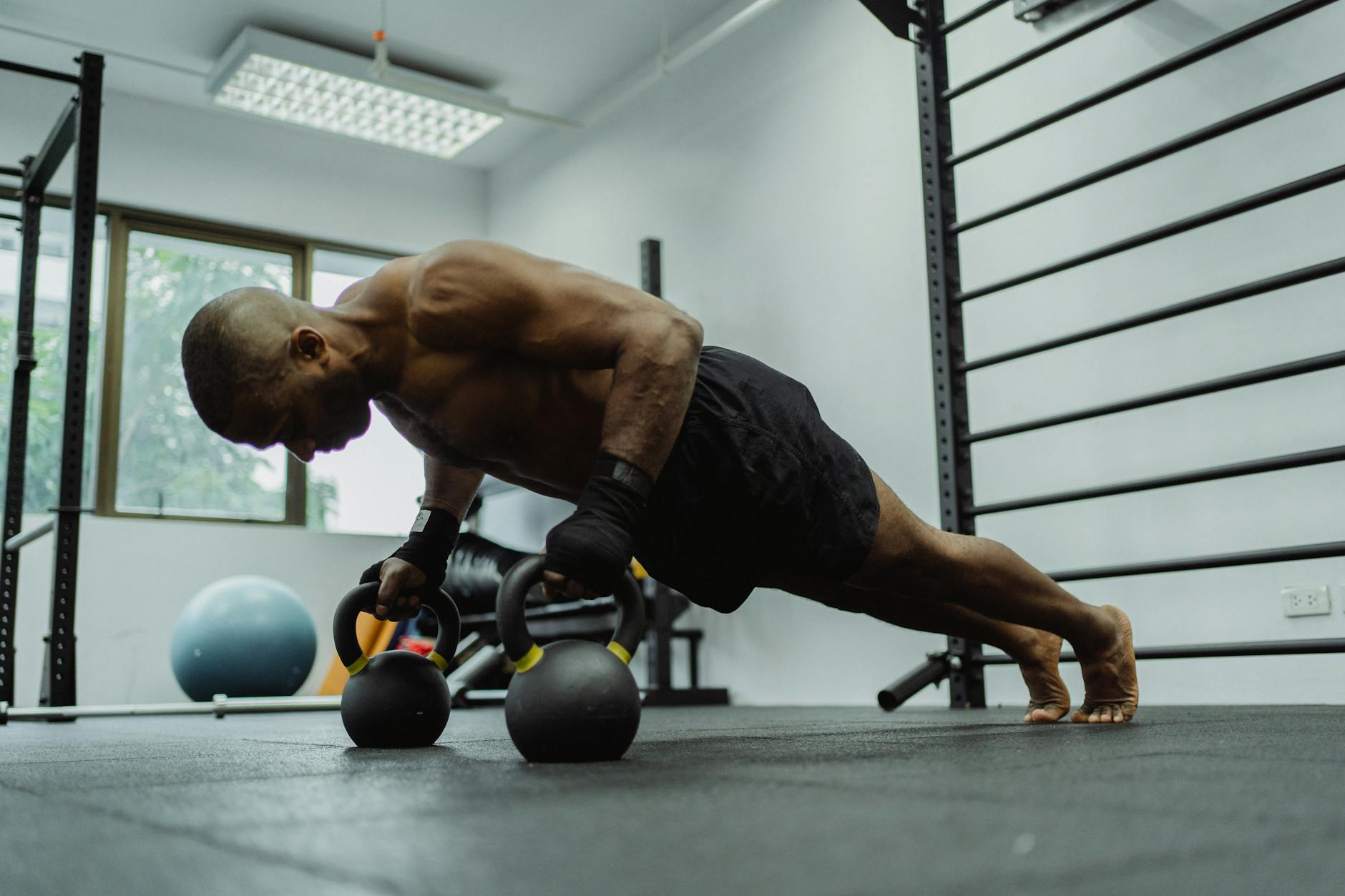 A fit man performs push-ups using kettlebells indoors, showcasing strength and fitness. - muscular endurance exercises