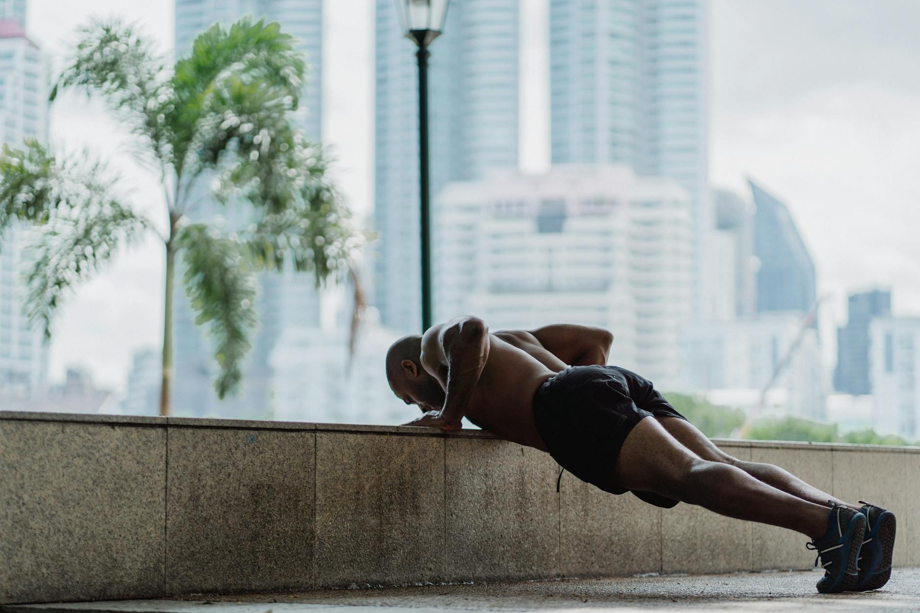 Strong man exercises outdoors, performing push-ups against a concrete wall. - muscular endurance exercises