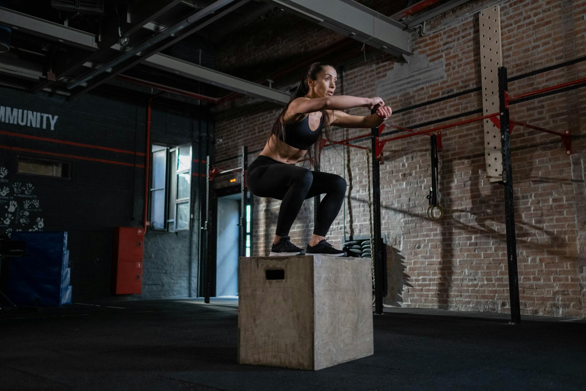 Female athlete performing box jumps in a gym, showcasing strength and agility training indoors. - muscular endurance exercises