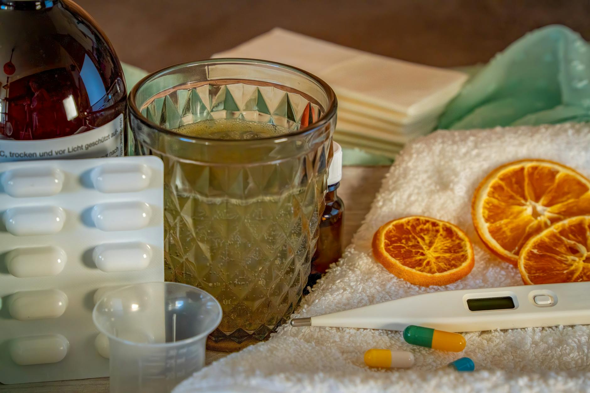 A collection of home remedies and medications for treating cold and flu symptoms, including a thermometer, pills, and herbal tea. - natural allergy relief