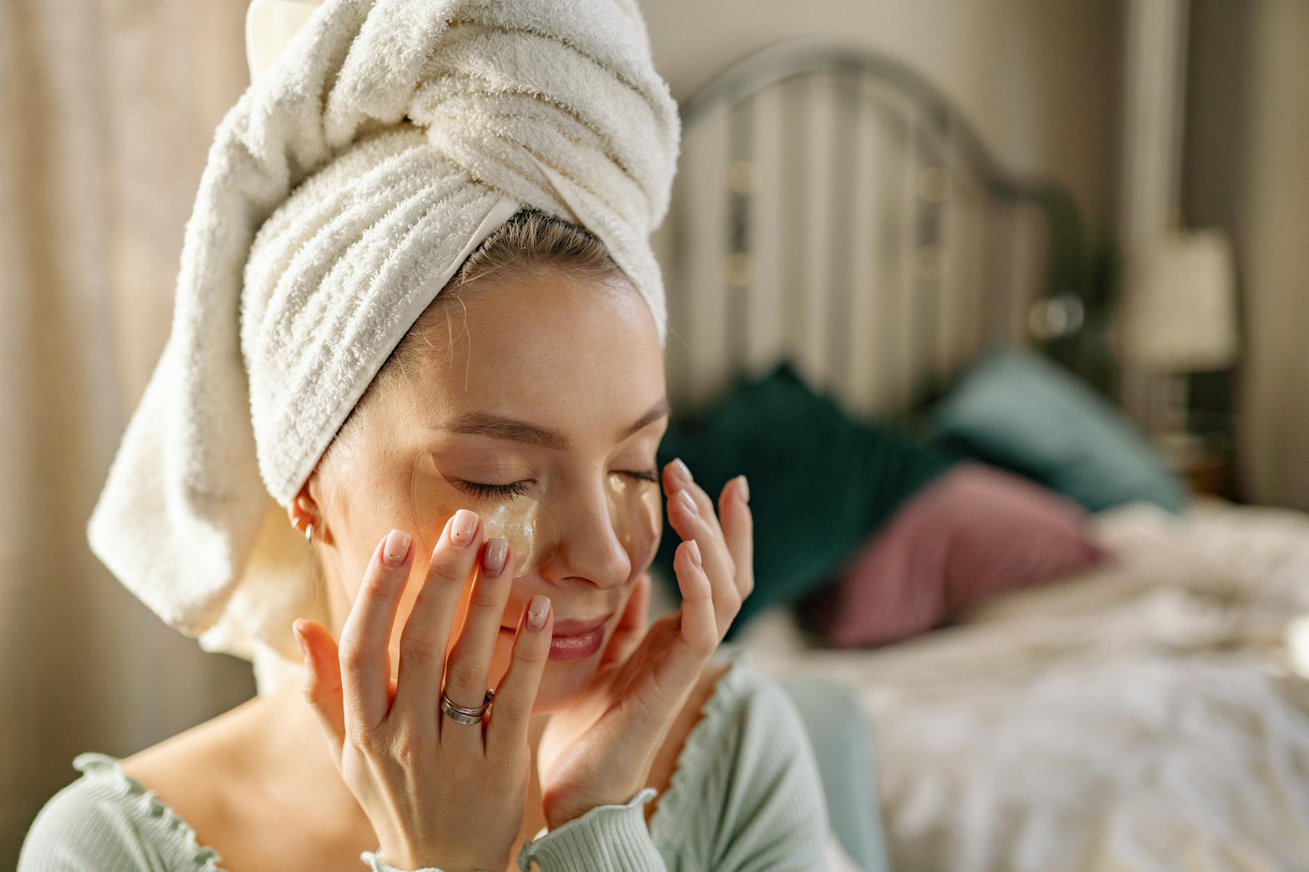 Woman enjoying a skincare routine with an under eye mask in a cozy bedroom setting. - natural anti aging skin