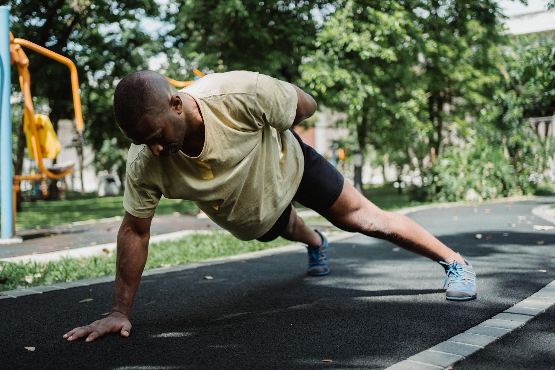 Adult man performing push-ups outdoors, promoting a healthy lifestyle and fitness. - outdoor bodyweight workout