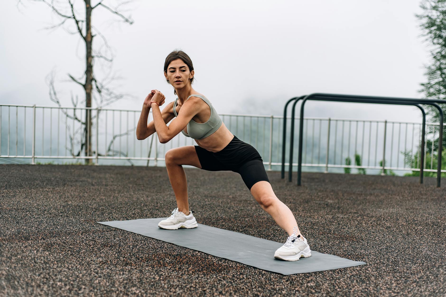 Woman exercising outdoors on yoga mat with a scenic view, embracing a healthy lifestyle. - outdoor hiit workouts
