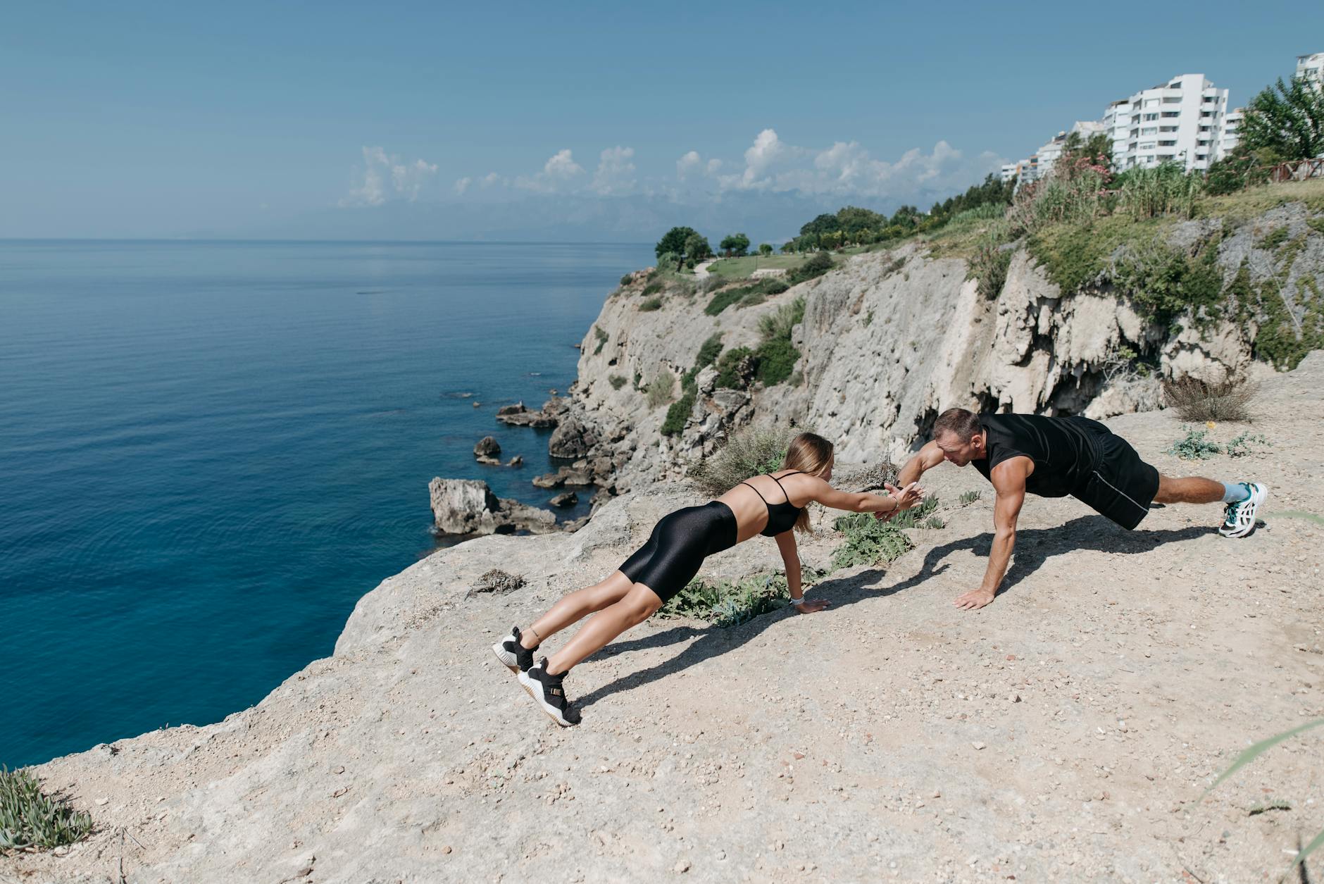 Fitness couple engaging in outdoor exercise on scenic seaside cliffs, promoting active lifestyle. - outdoor hiit workouts