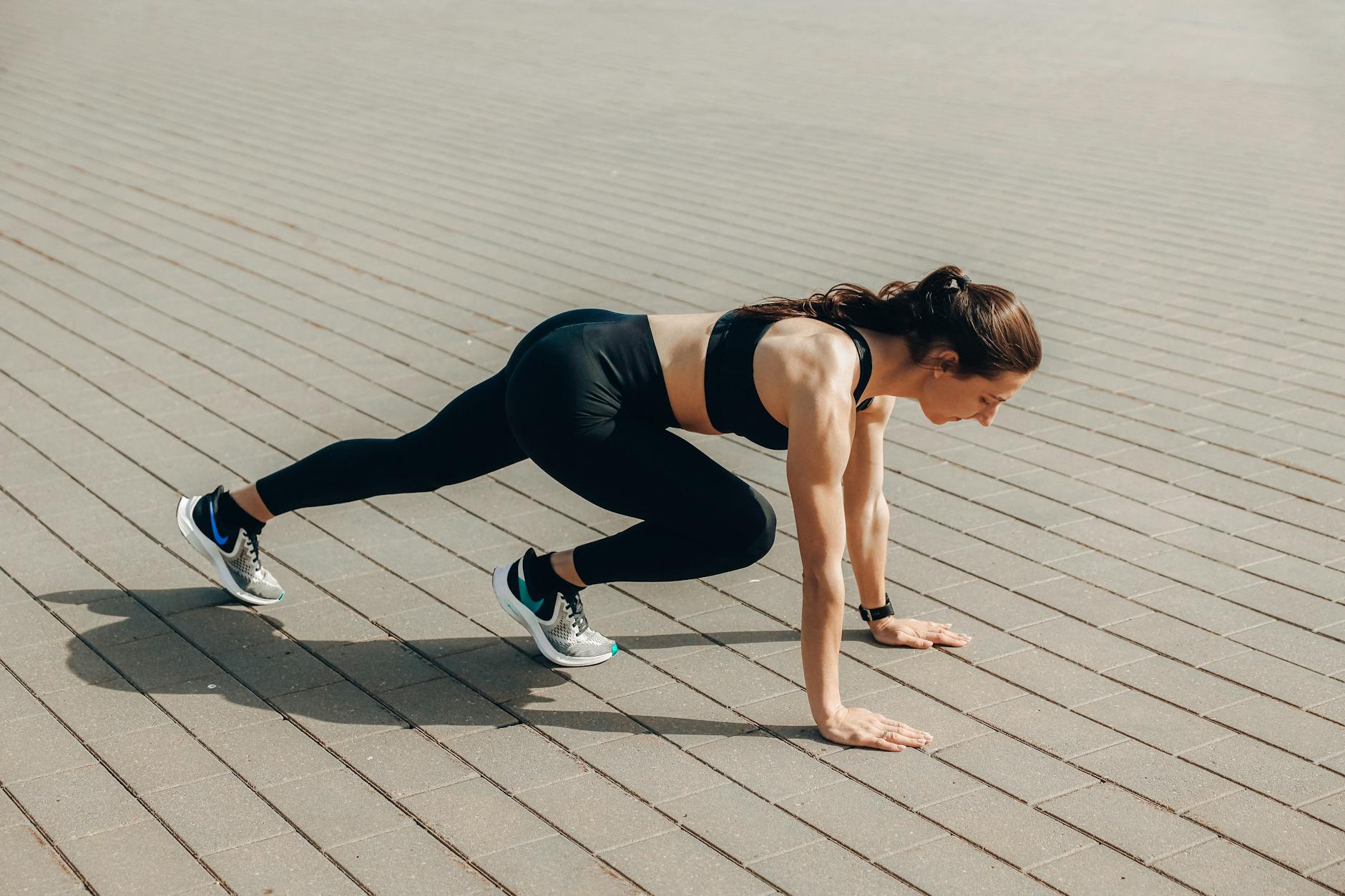 Woman in black sportswear doing an outdoor workout on a sunny day. - outdoor interval training