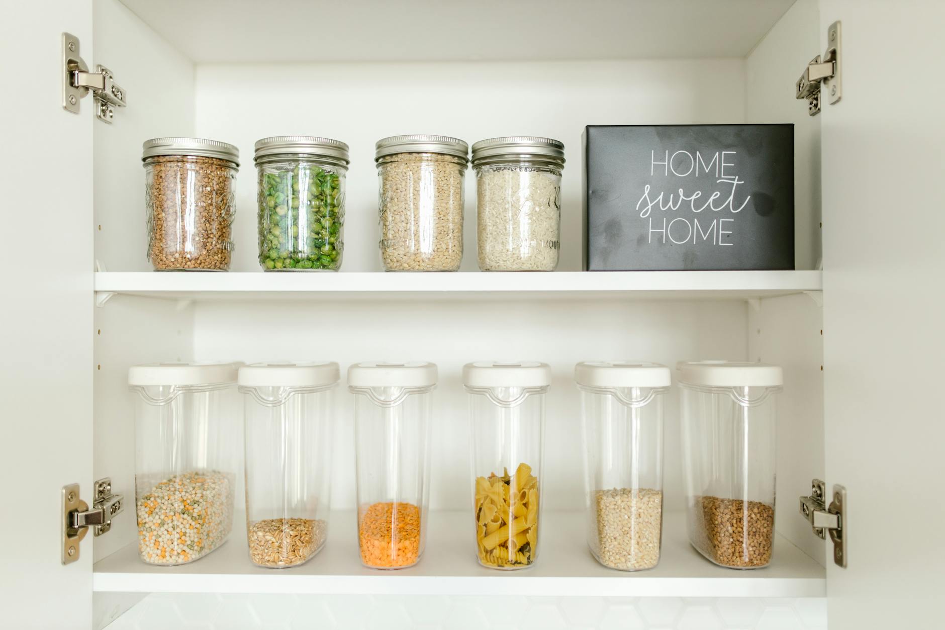Neatly arranged glass and plastic jars containing grains and pasta in a kitchen cabinet. - pantry cleanout weight loss