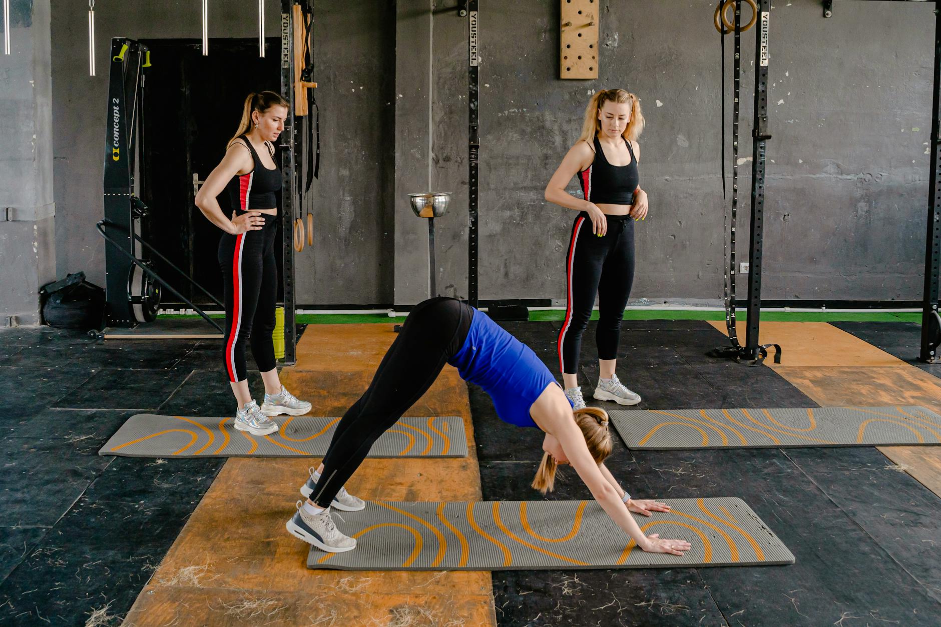 Three women engaged in yoga poses on mats in a gym environment, enhancing fitness and wellness. - posture exercises gym