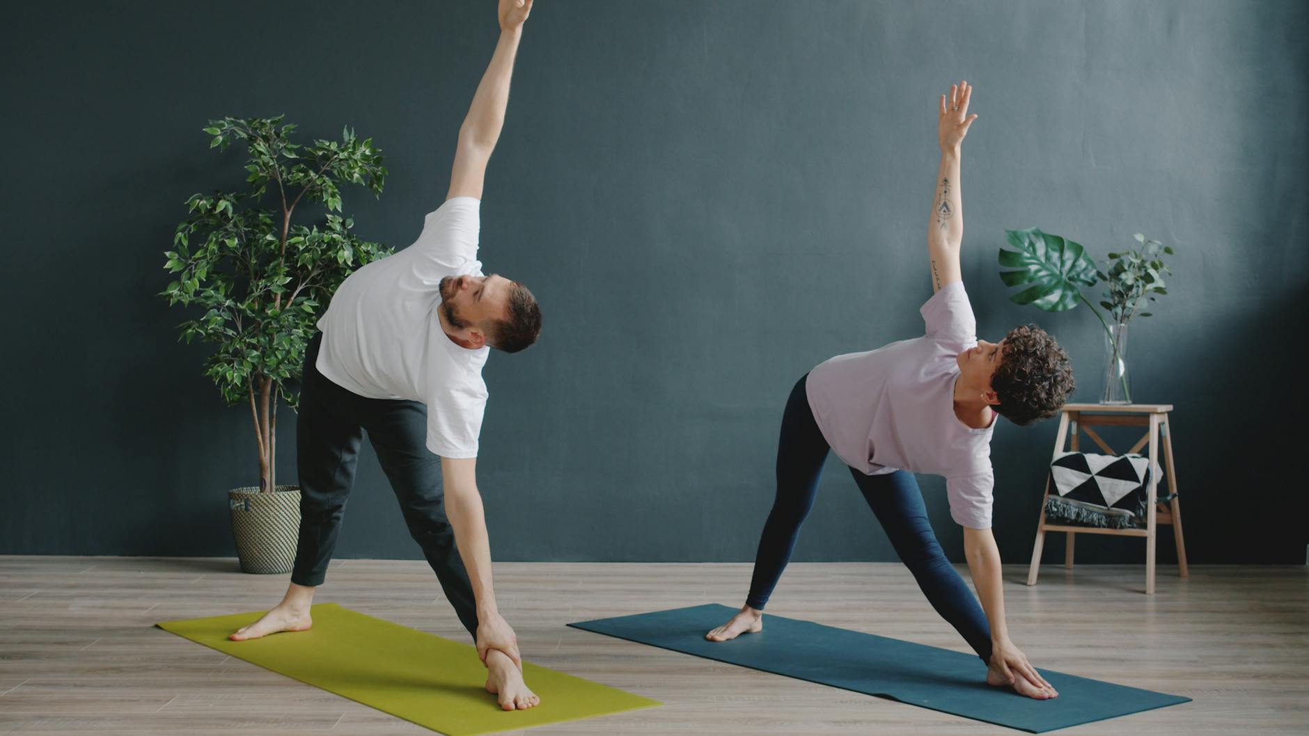 Two adults performing yoga on mats indoors, showing focus and flexibility. - posture exercises reddit