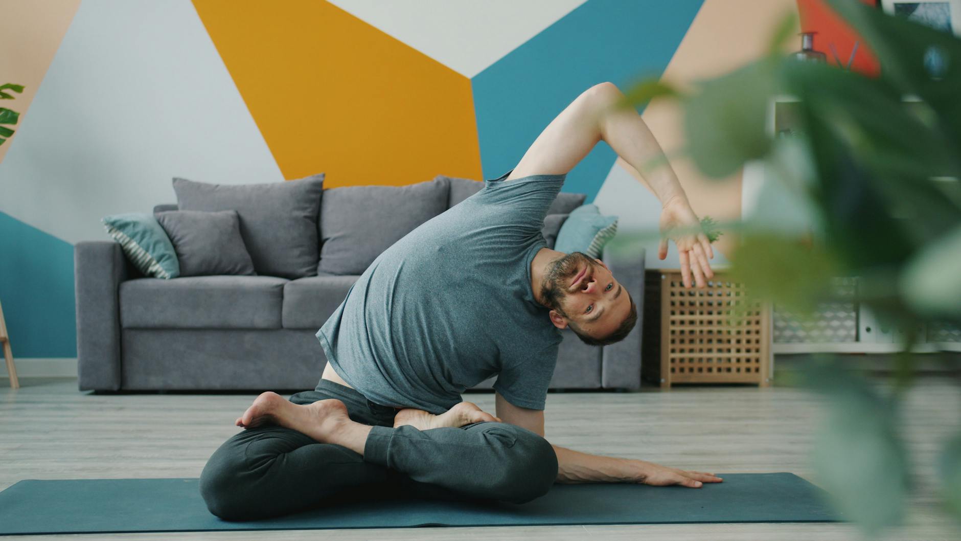 Adult male performs yoga pose indoors, showcasing flexibility and relaxation. - posture exercises reddit