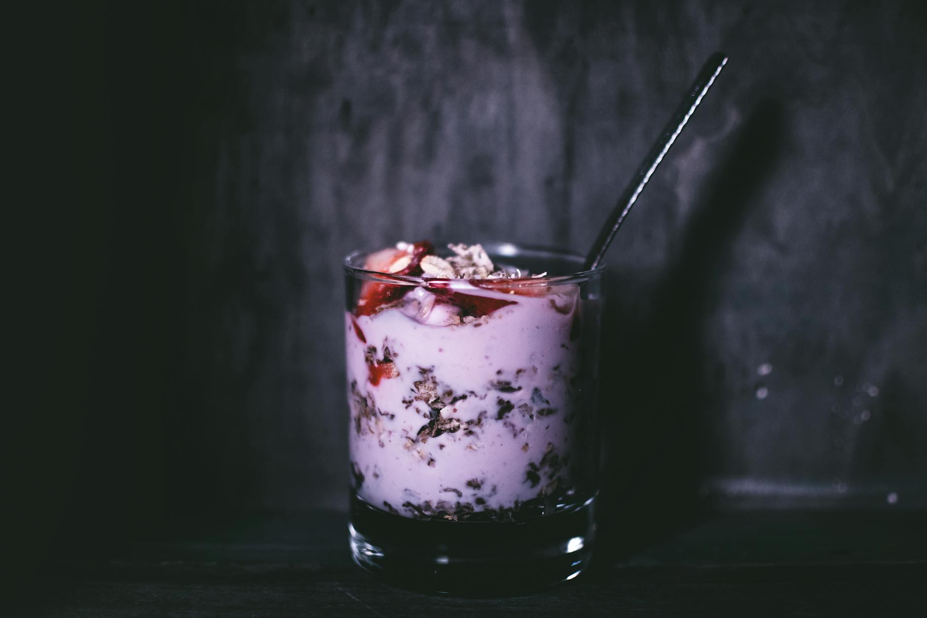 Dark, moody close-up of a delicious yogurt parfait with granola and berries in a glass. - probiotic recipes