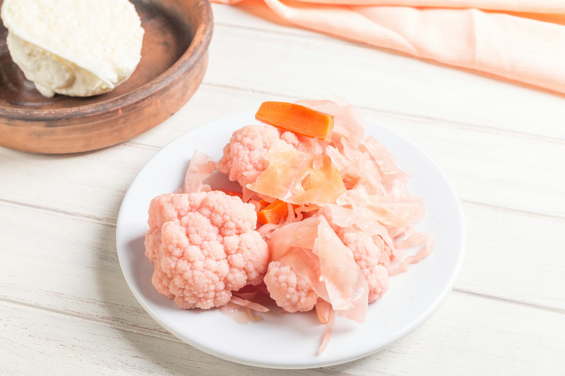 Pink pickled cauliflower and carrots on a white plate, perfect for culinary presentations. - probiotic recipes